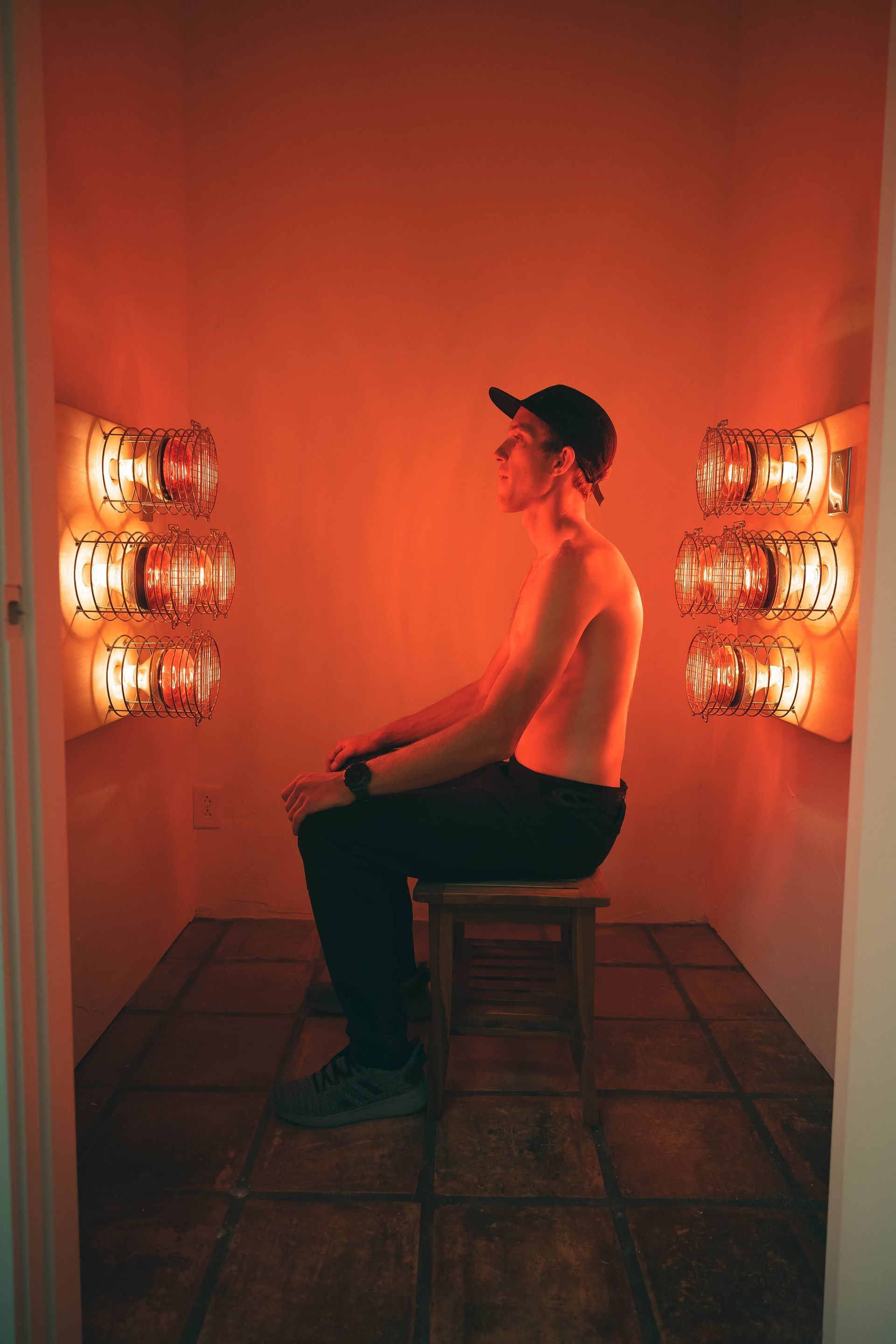 A man is sitting on a stool in a near infrared sauna.