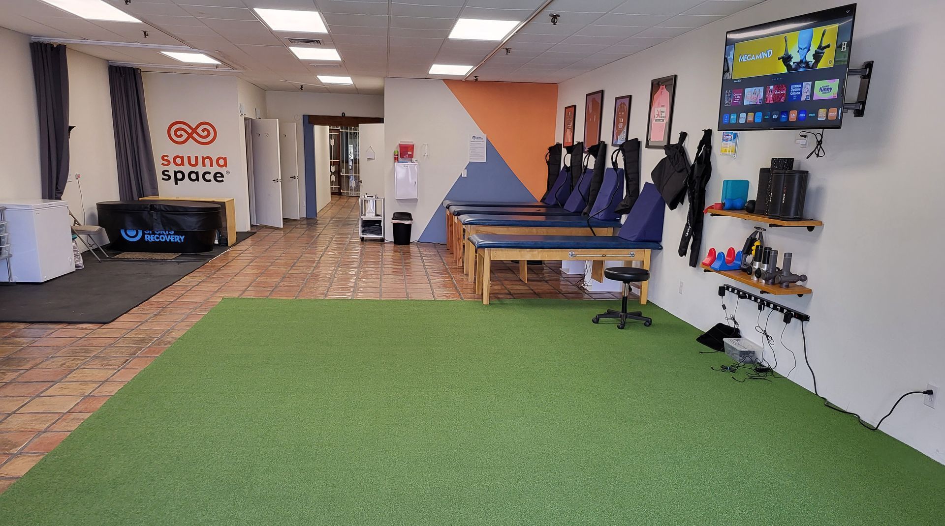 A large room with a green carpet and a television on the wall.