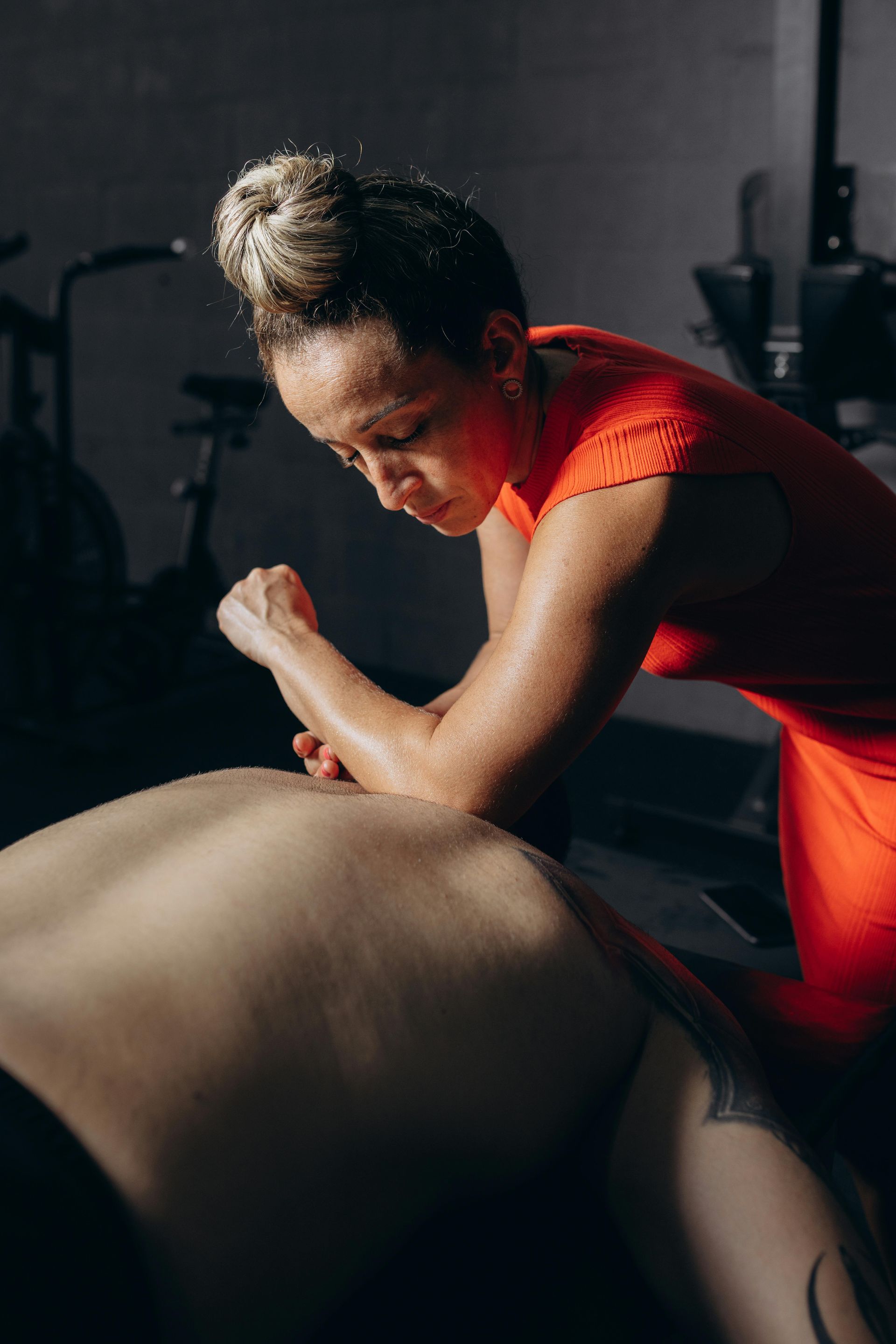 A woman is giving a man a massage in a gym.