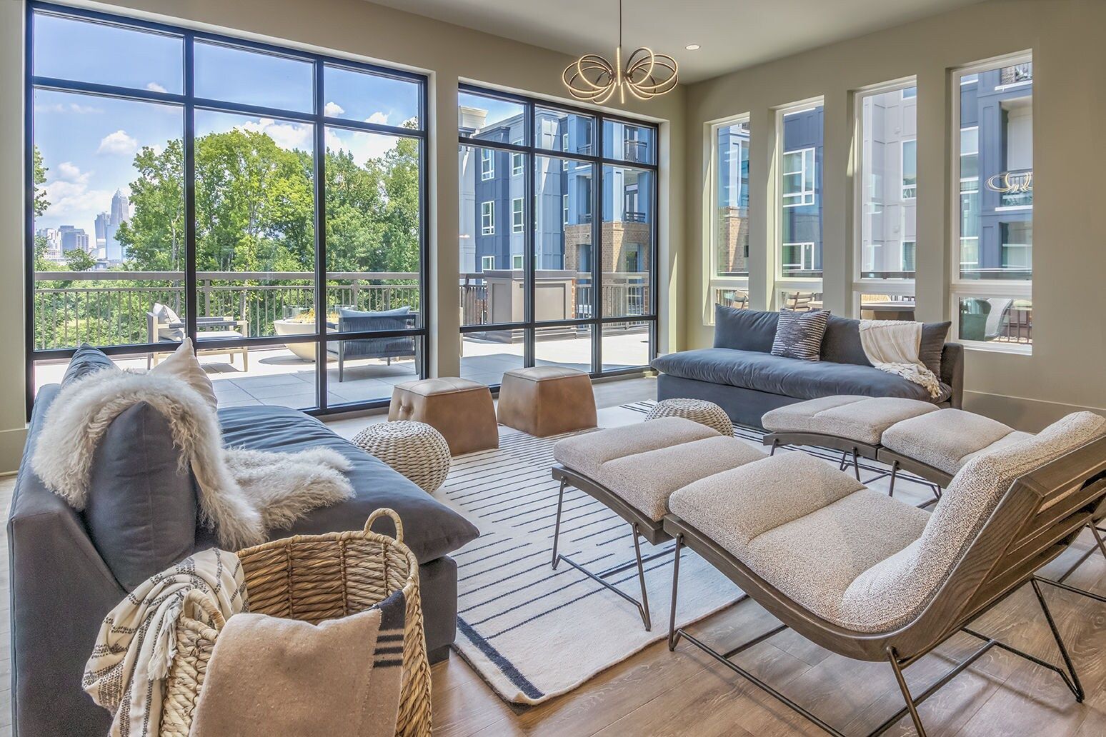 Living room with floor-to-ceiling windows, two sofas, lounge chairs, a rug, and a woven basket.