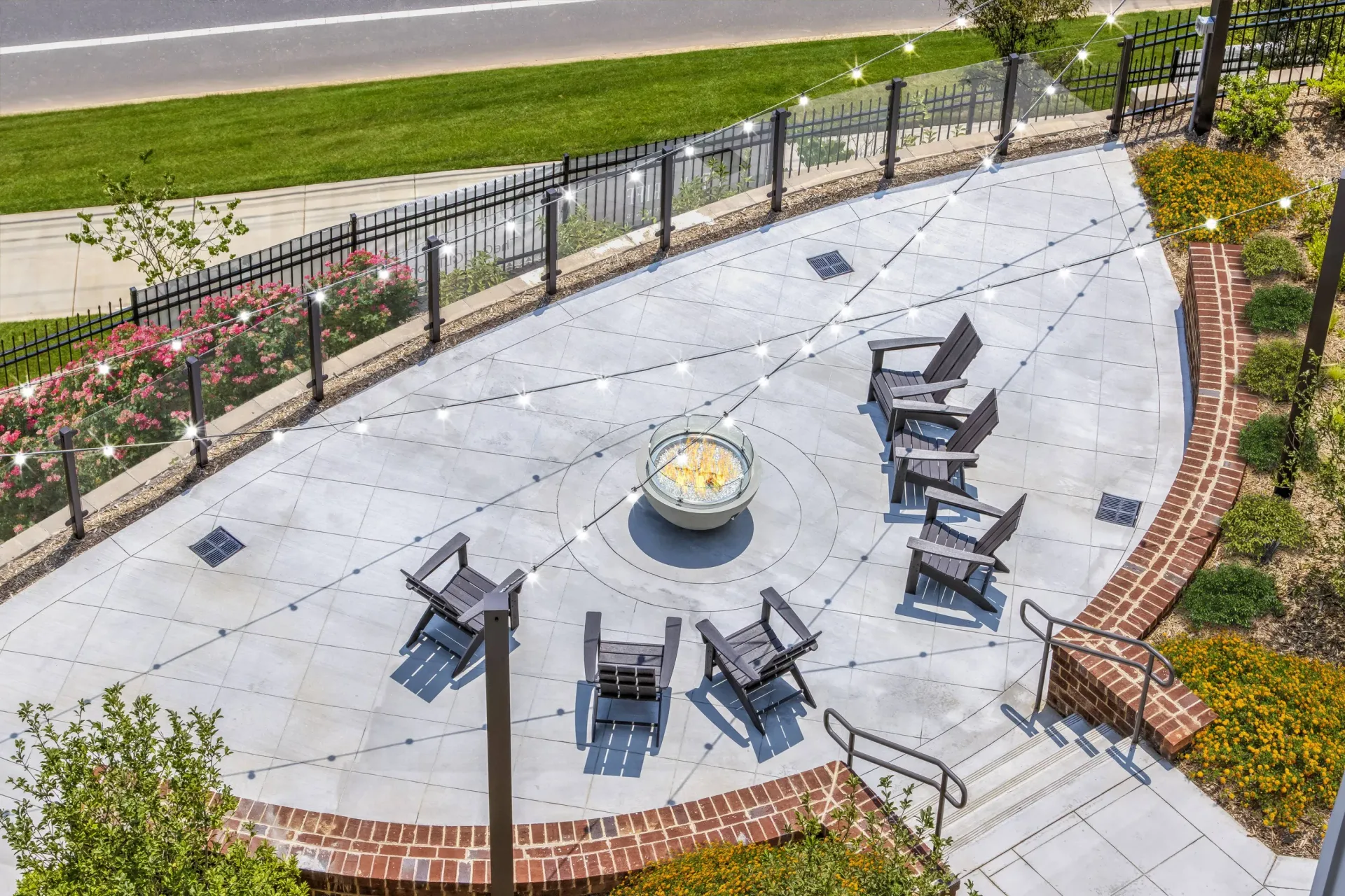 Aerial view of a circular outdoor patio with a fire pit, string lights, and surrounding seating.
