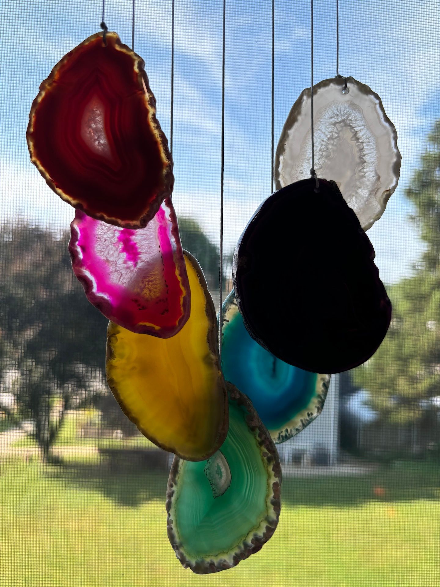 Pilates and Intuitive Energy Healing. wind chime made of agate slices is hanging from a window.
