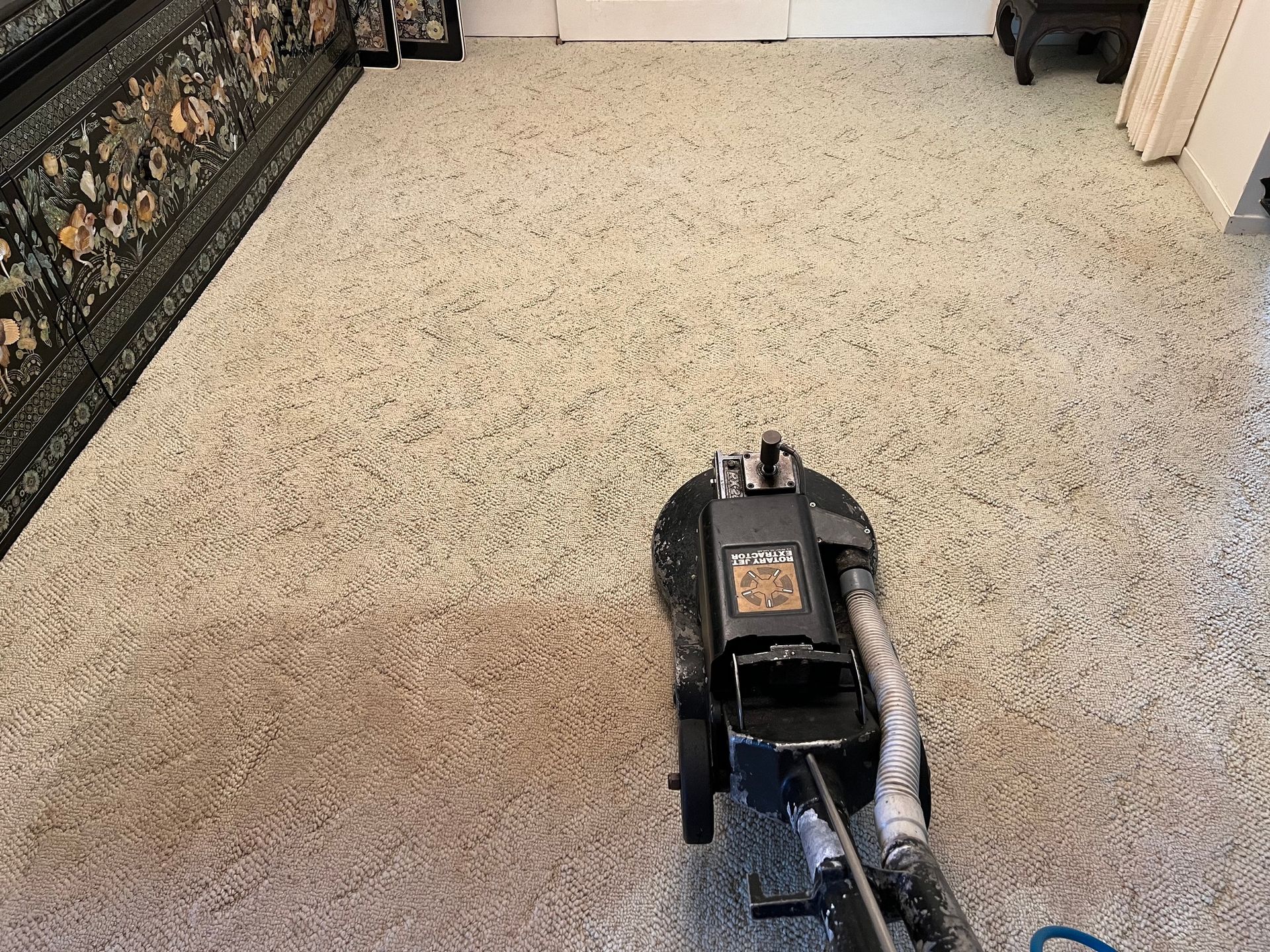 A vacuum cleaner is cleaning a carpet in a living room.