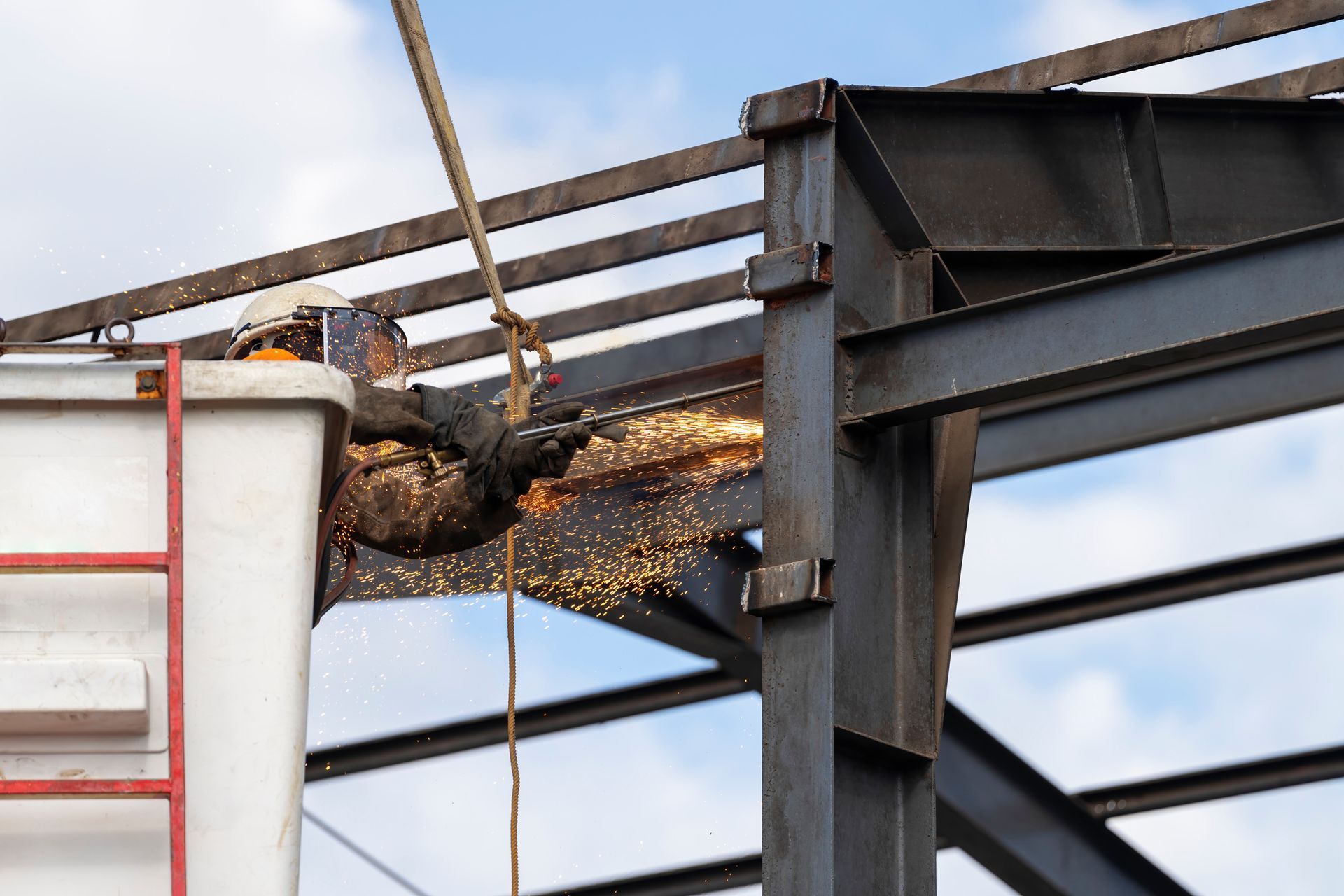 A man is cutting a metal structure with a grinder.