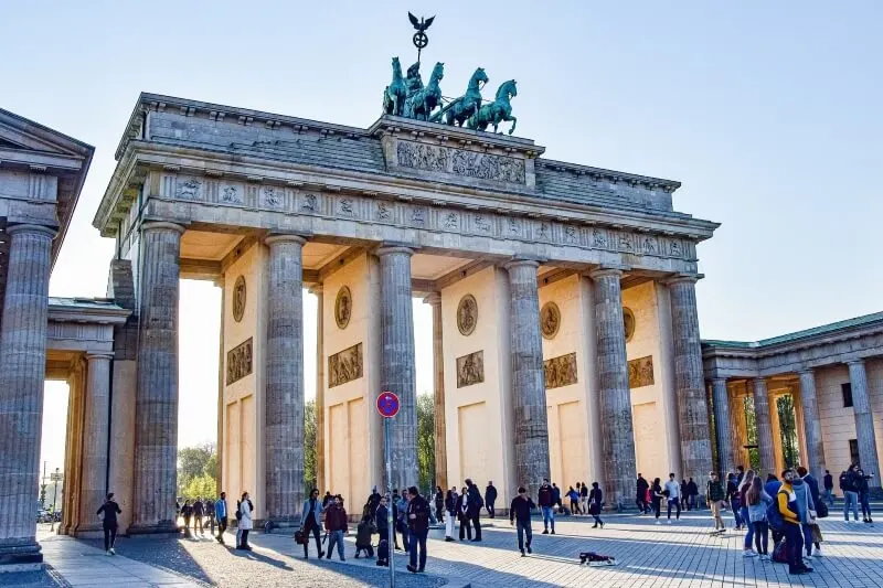 a group of people are standing in front of the berlin gate .