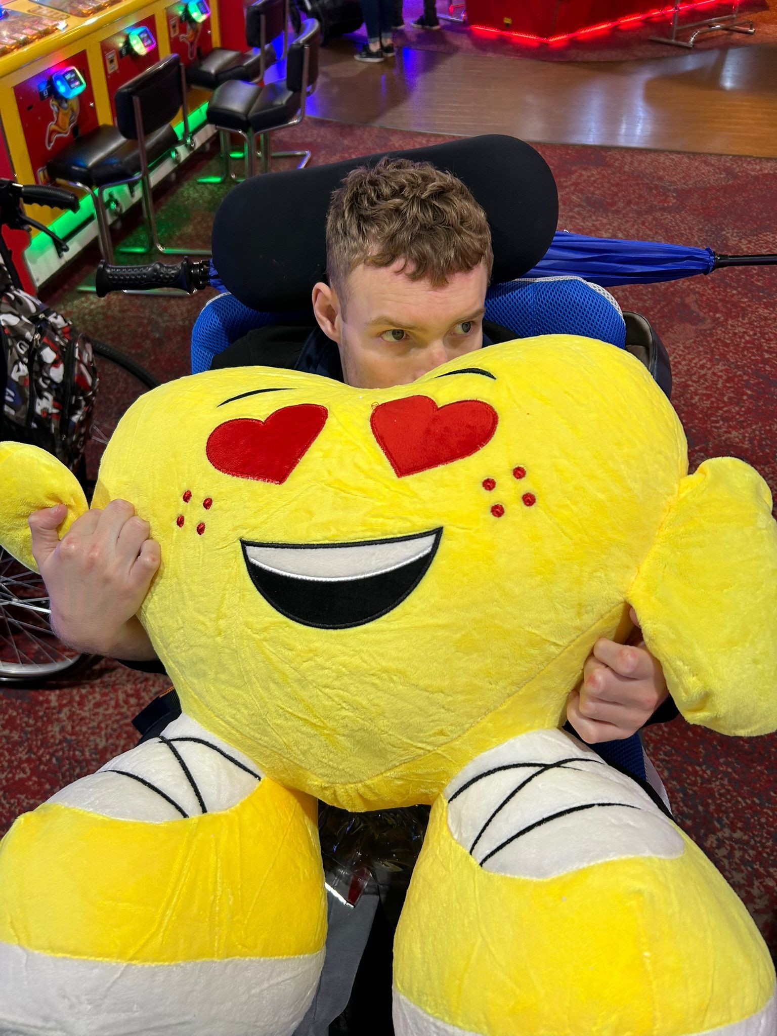 a young man holding a soft pillow in the shape of a heart with heart eyes