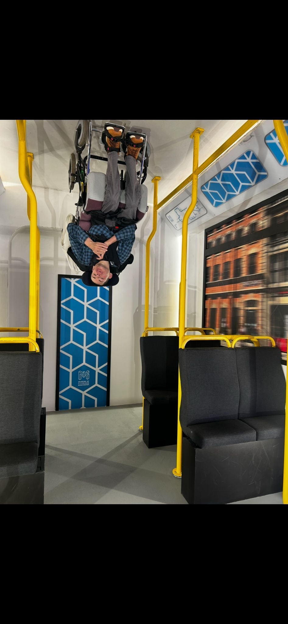 Person upside down inside bus-themed room; yellow railings, blue geometric door.
