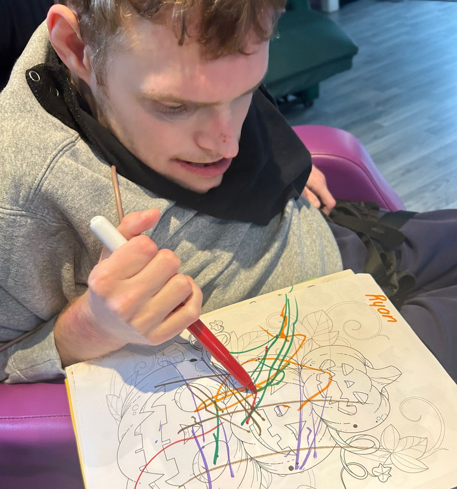 Man with disability drawing with colorful markers, indoors.