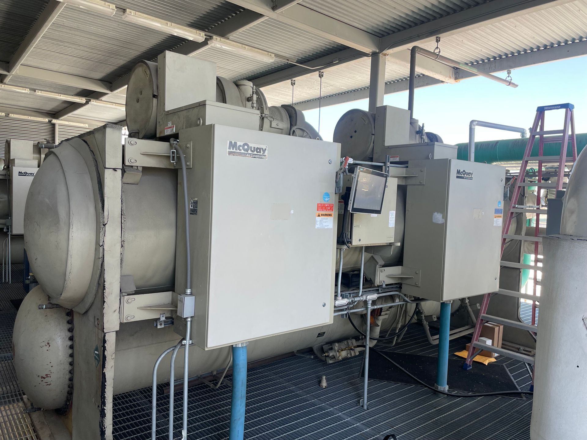 A large machine is sitting under a roof in a factory.