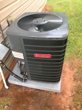 A large air conditioner is sitting outside of a house.