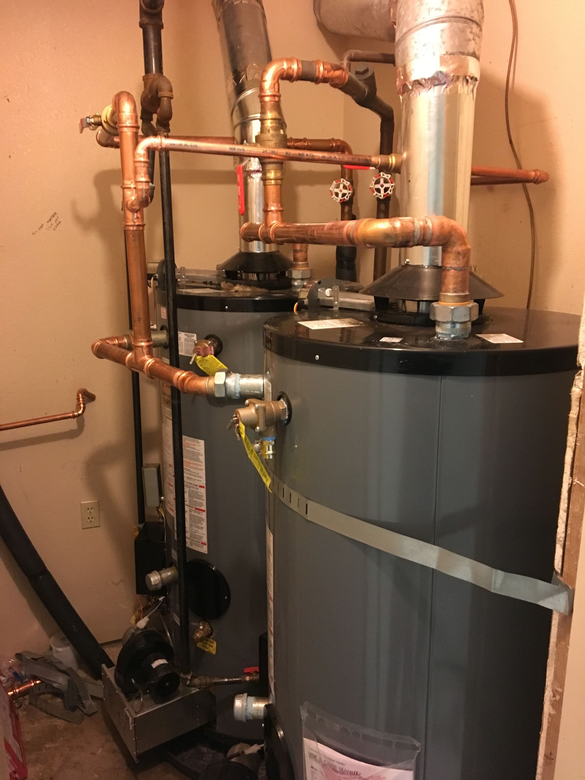 Two water heaters in a room with copper pipes