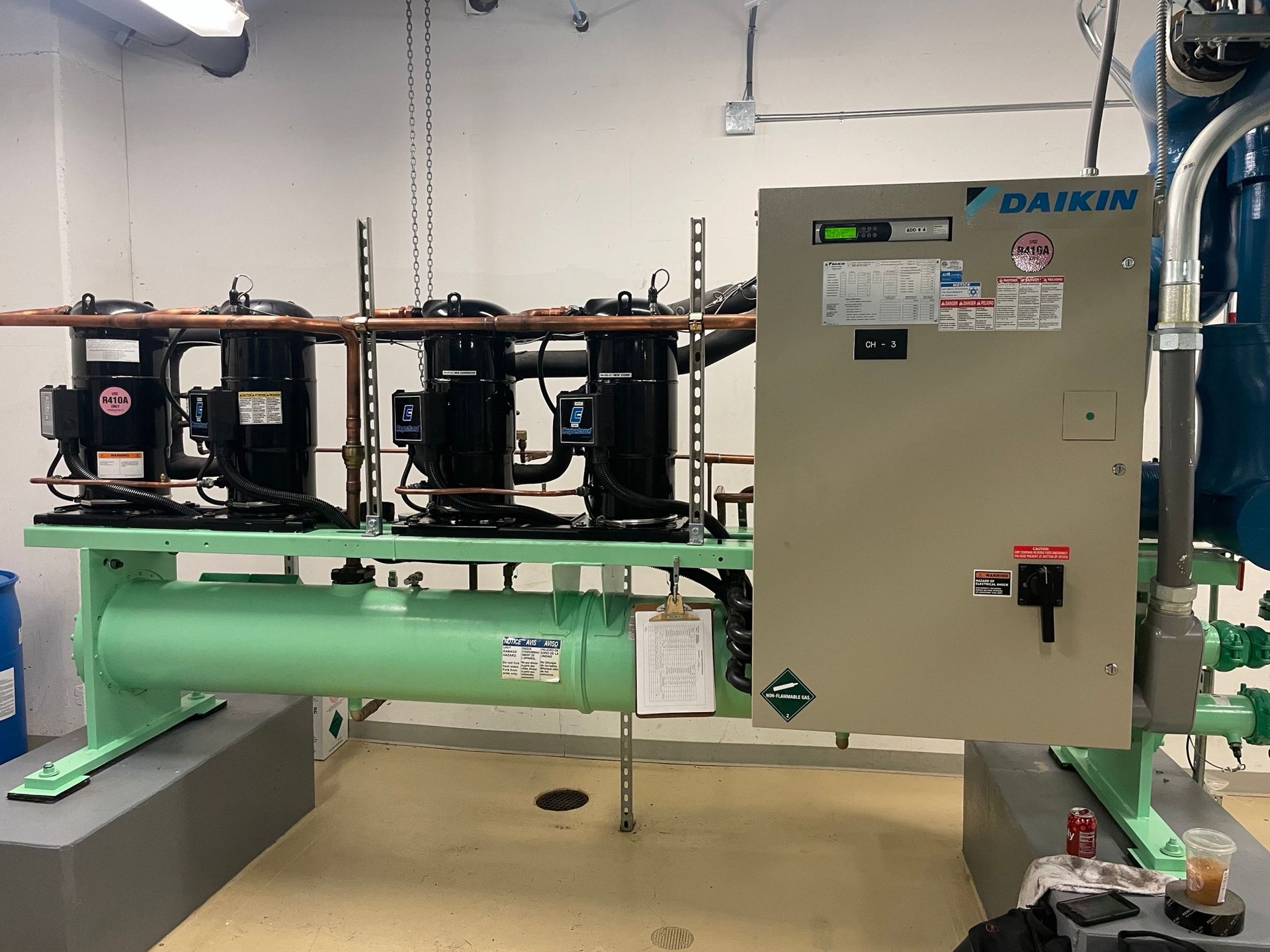 A daikin compressor is sitting in a room next to a control panel.