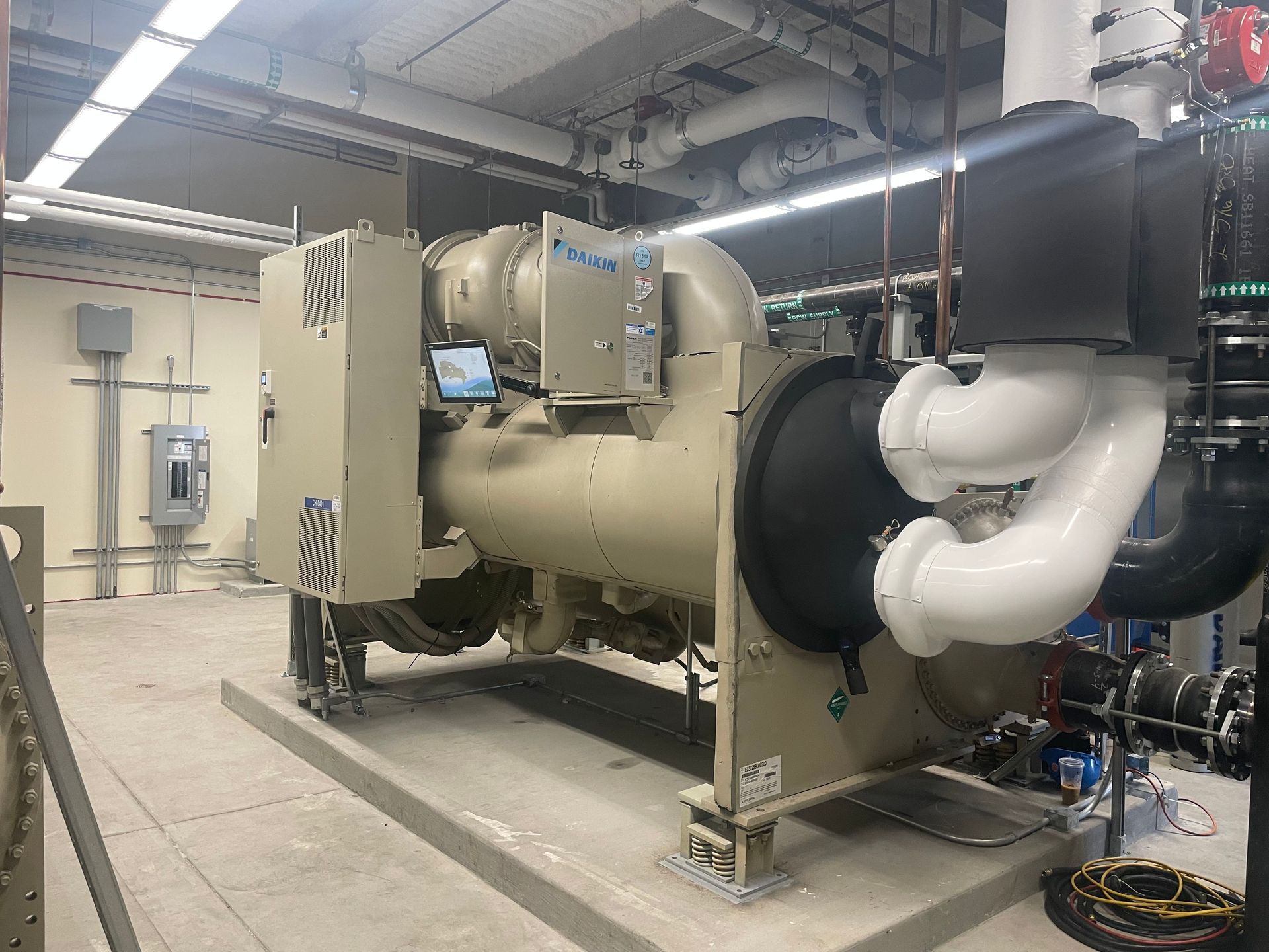 A large machine is sitting in a room with pipes.