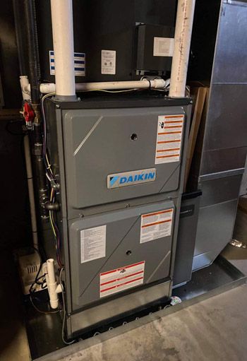 A daikin air conditioner is sitting on top of a concrete floor in a basement.