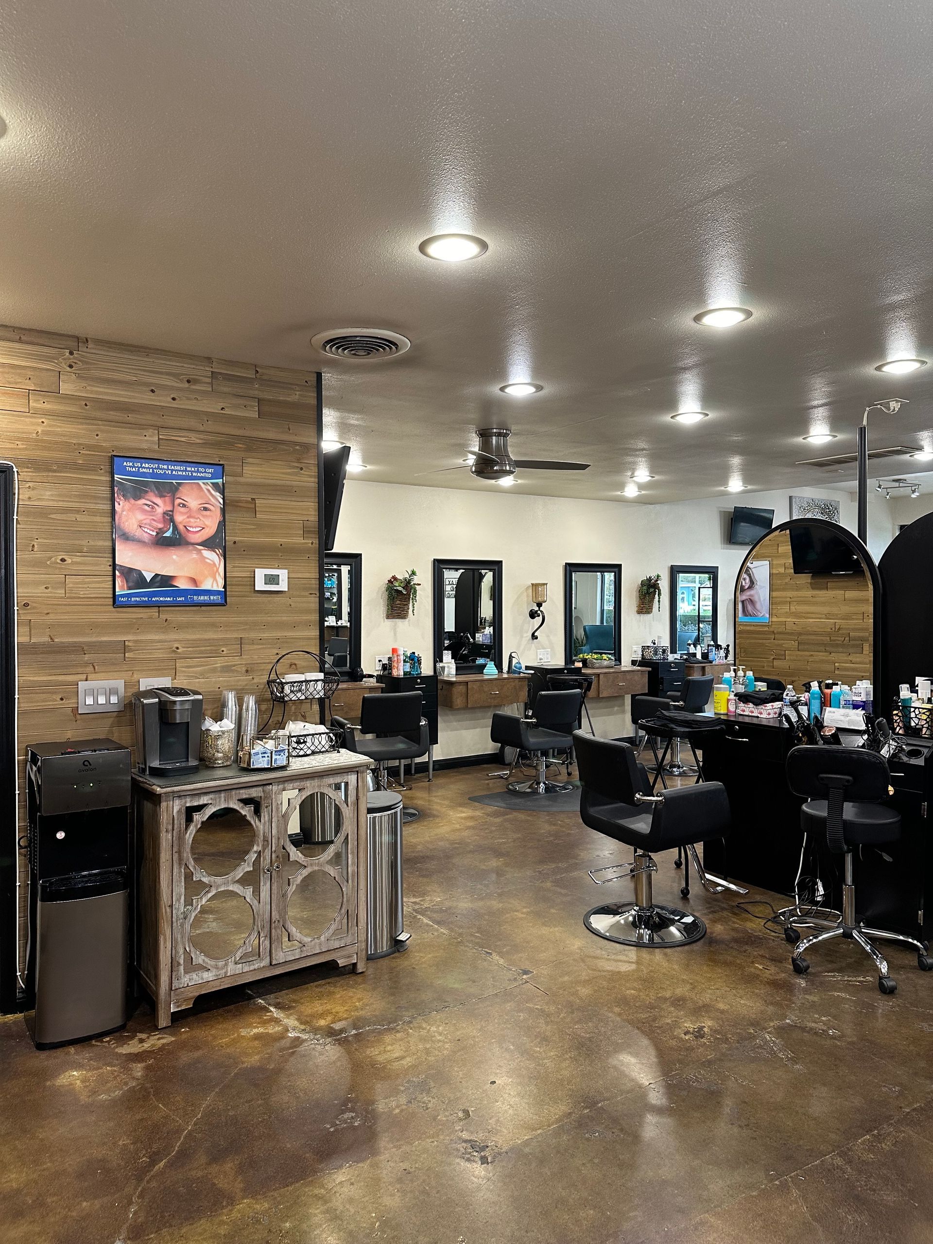 Hair salon interior with work stations, mirrors, and wood accent wall.