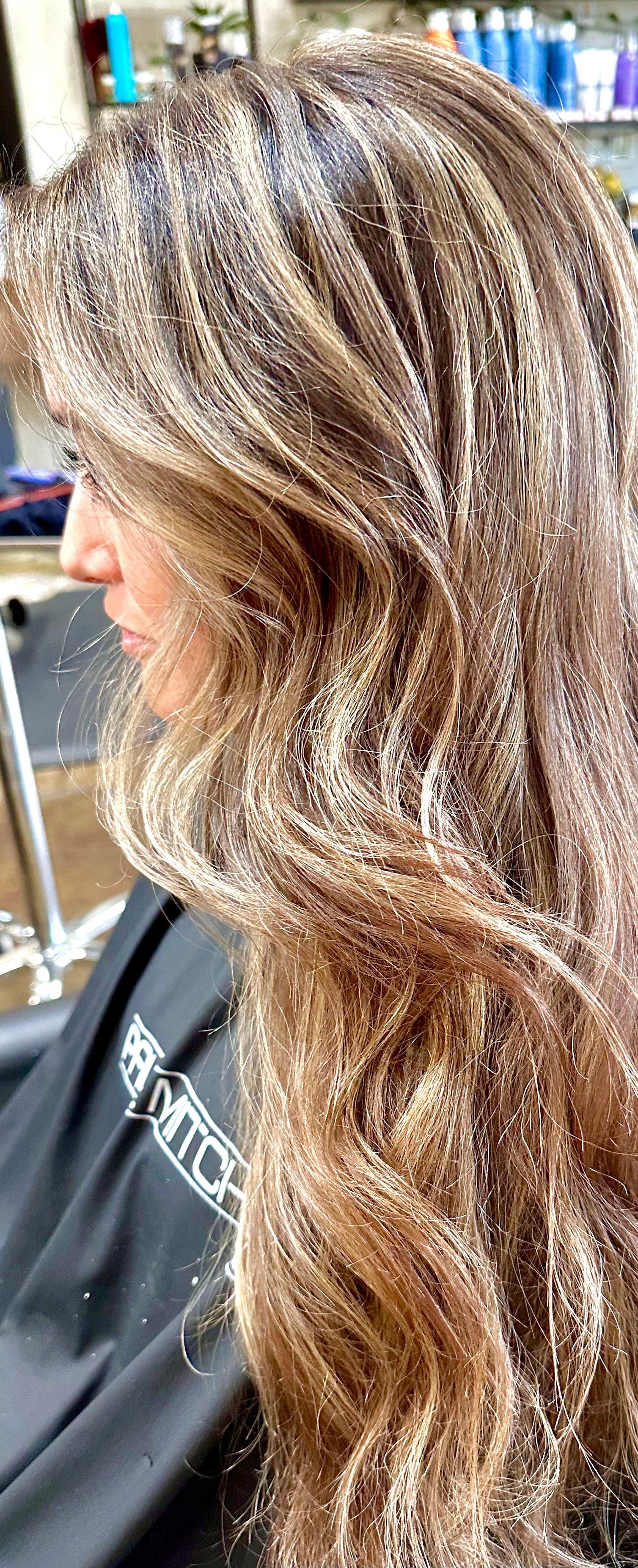 Woman with long wavy brown and blonde highlighted hair.