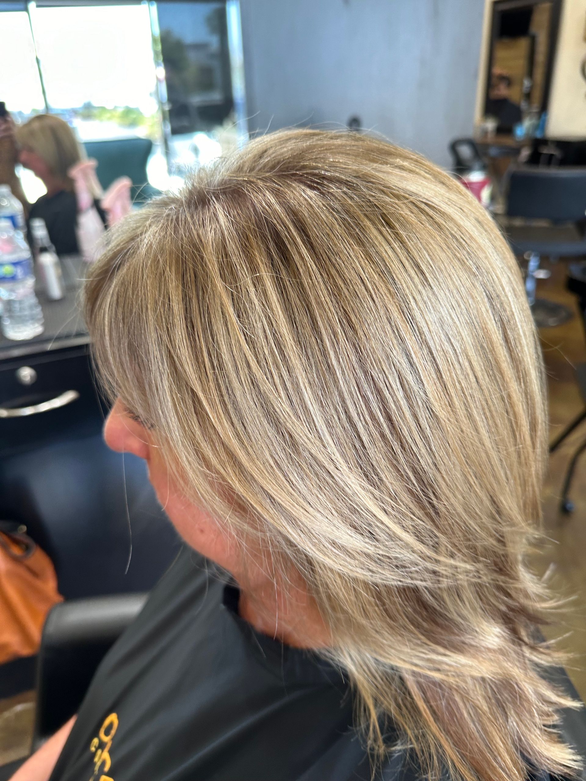 Woman with layered, blonde highlighted hair in a salon chair.
