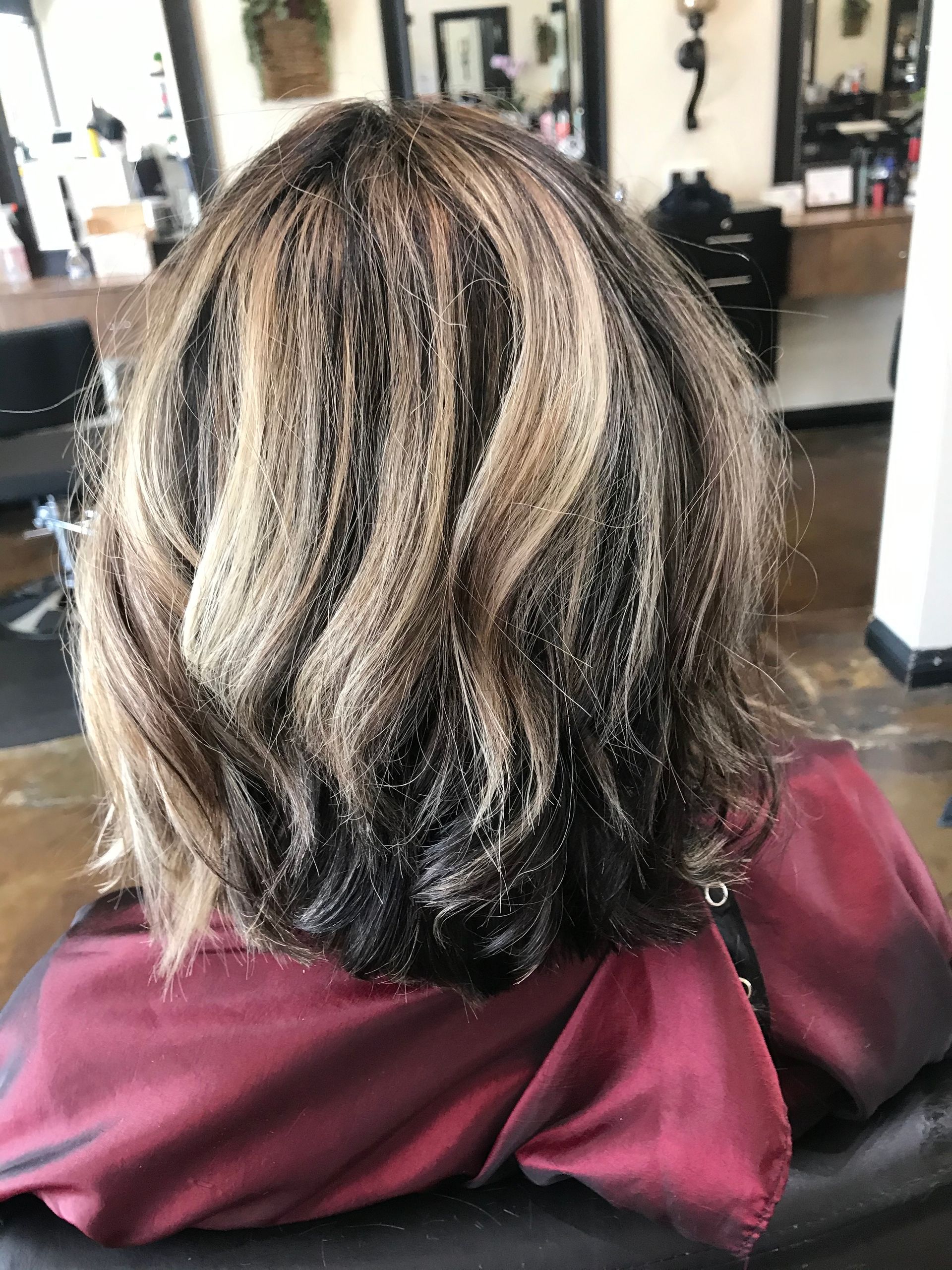 Woman with long, highlighted brown hair in front of a wooden backdrop.