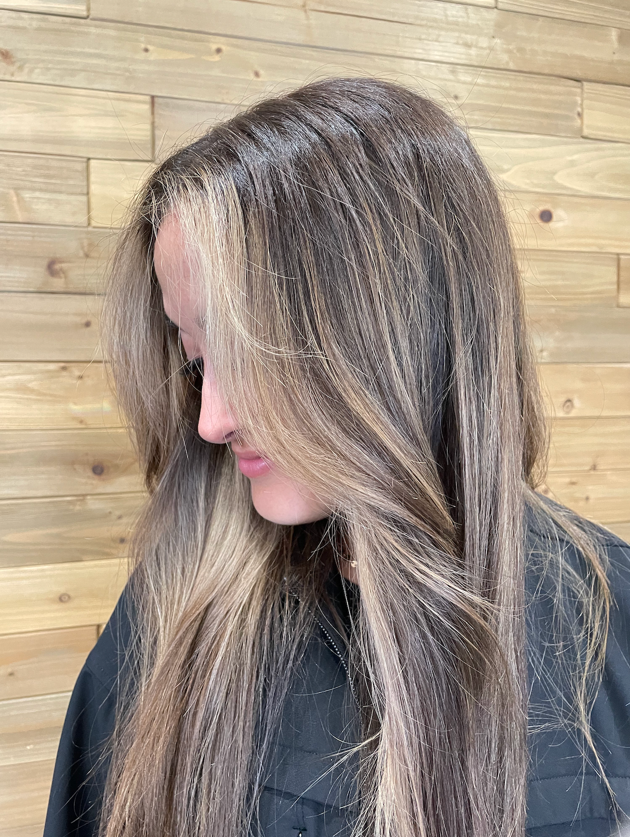 Woman's short, wavy hair with blonde highlights and dark roots, in a salon setting.