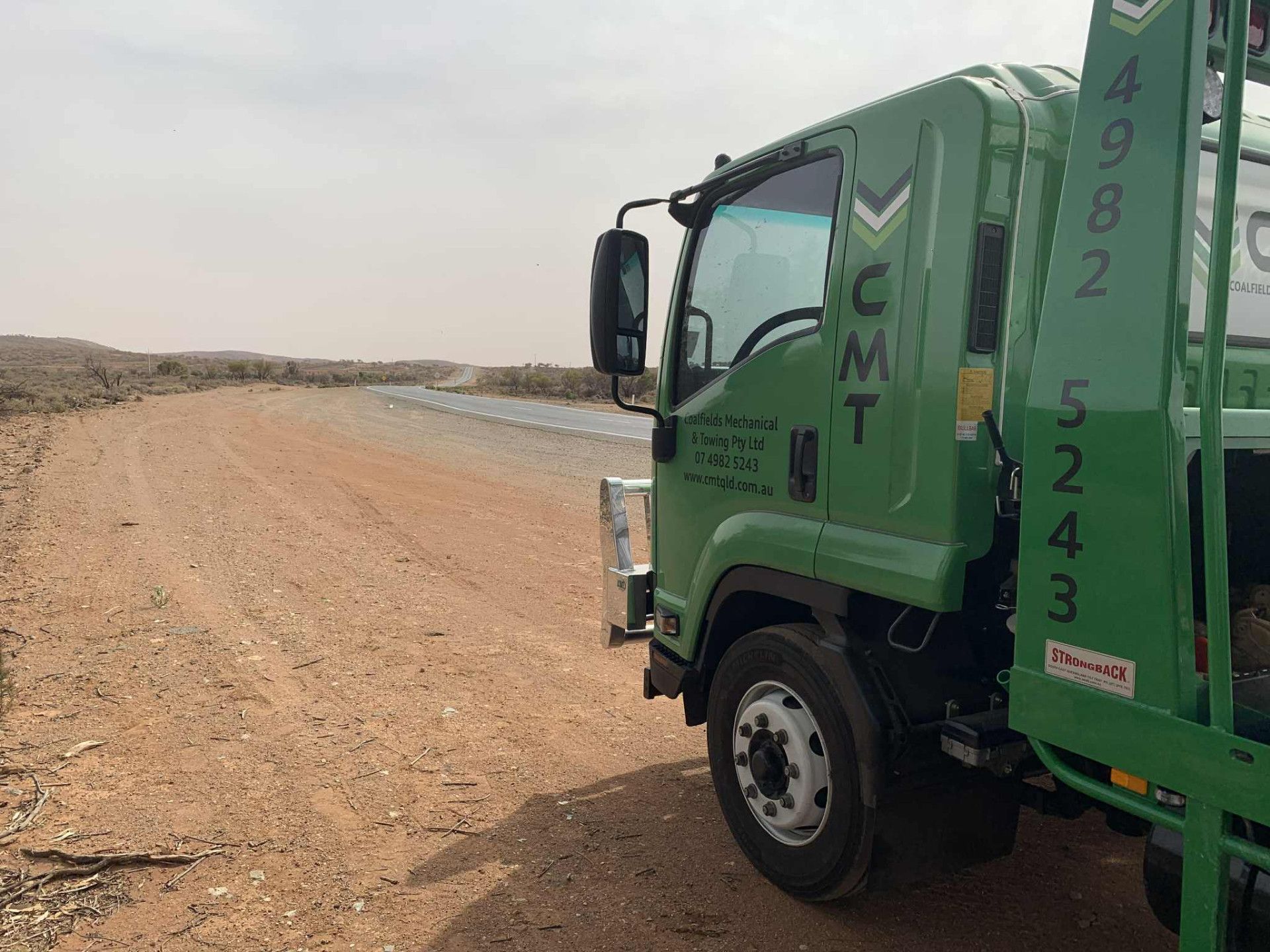 Green CMT truck parked on a dusty dirt road, desert setting.— Coalfields Mechanical & Towing in Blackwater, QLD