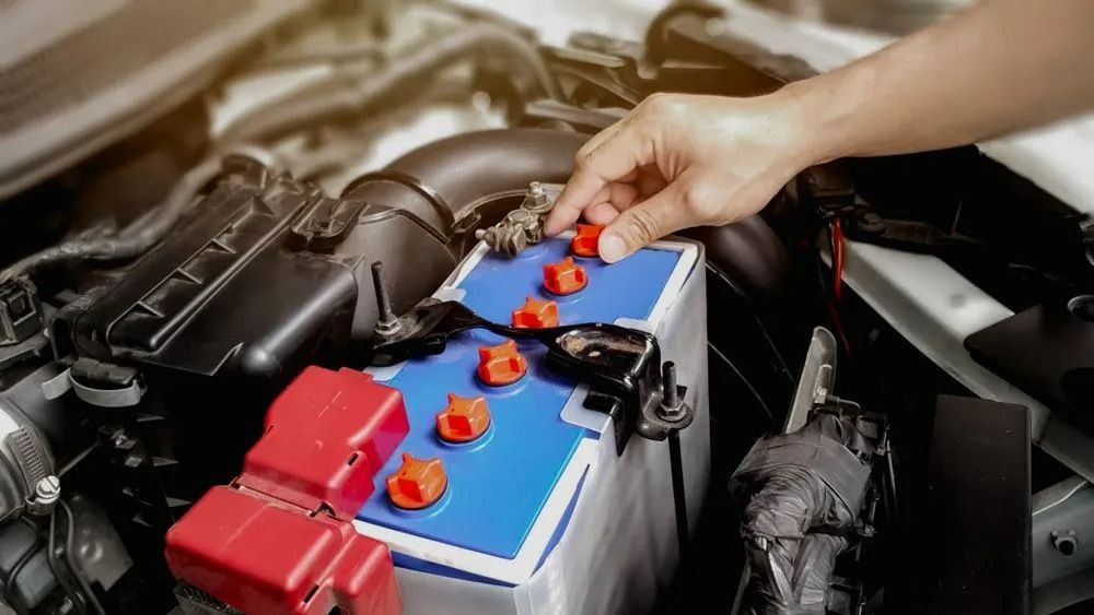 A Person Is Plugging a Battery Into a Car — Coalfields Mechanical & Towing in Blackwater, QLD