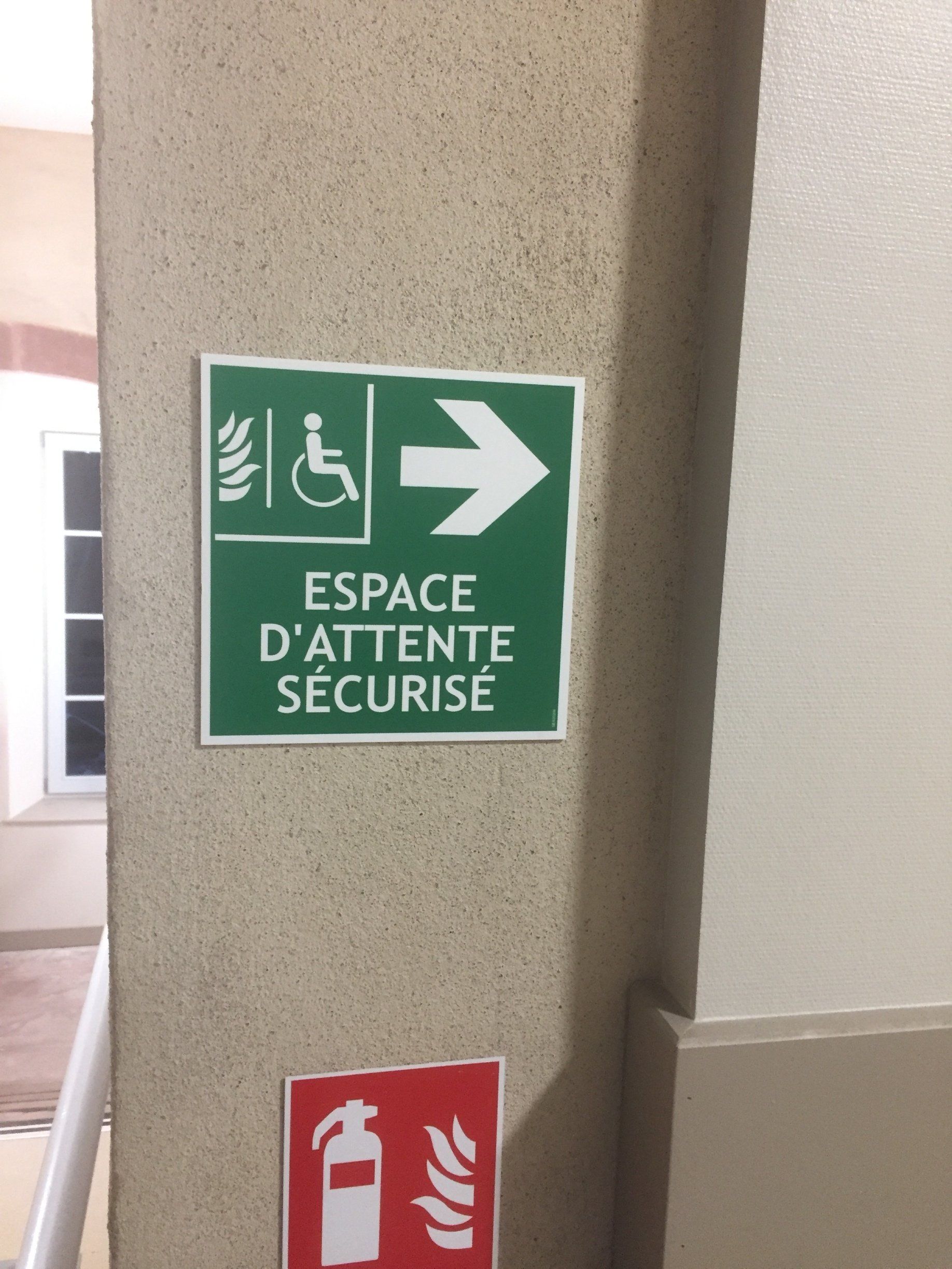 Un panneau vert sur un mur qui dit espace d'attente sécurité