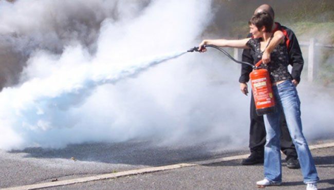 Une femme utilise un extincteur pour éteindre un incendie