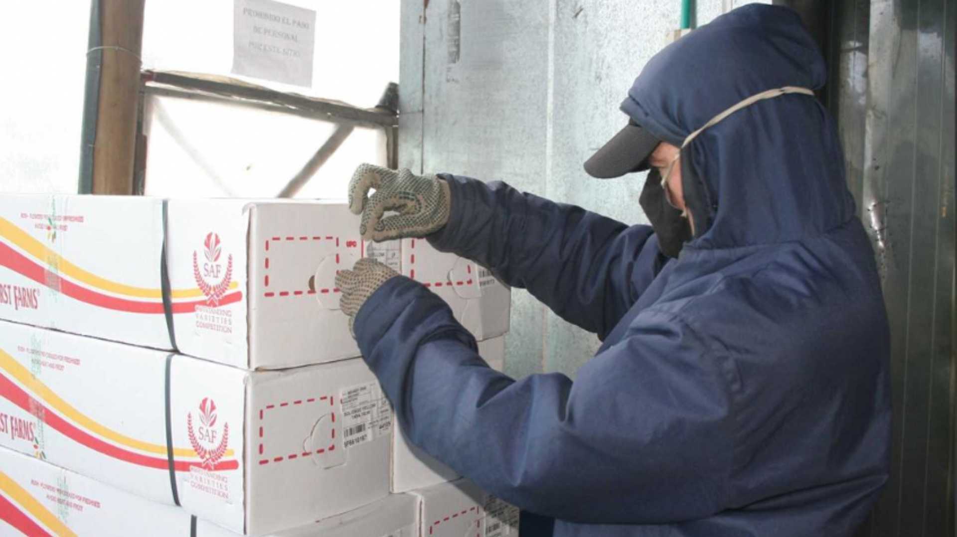 un hombre con una chaqueta con capucha está trabajando en una pila de cajas.
