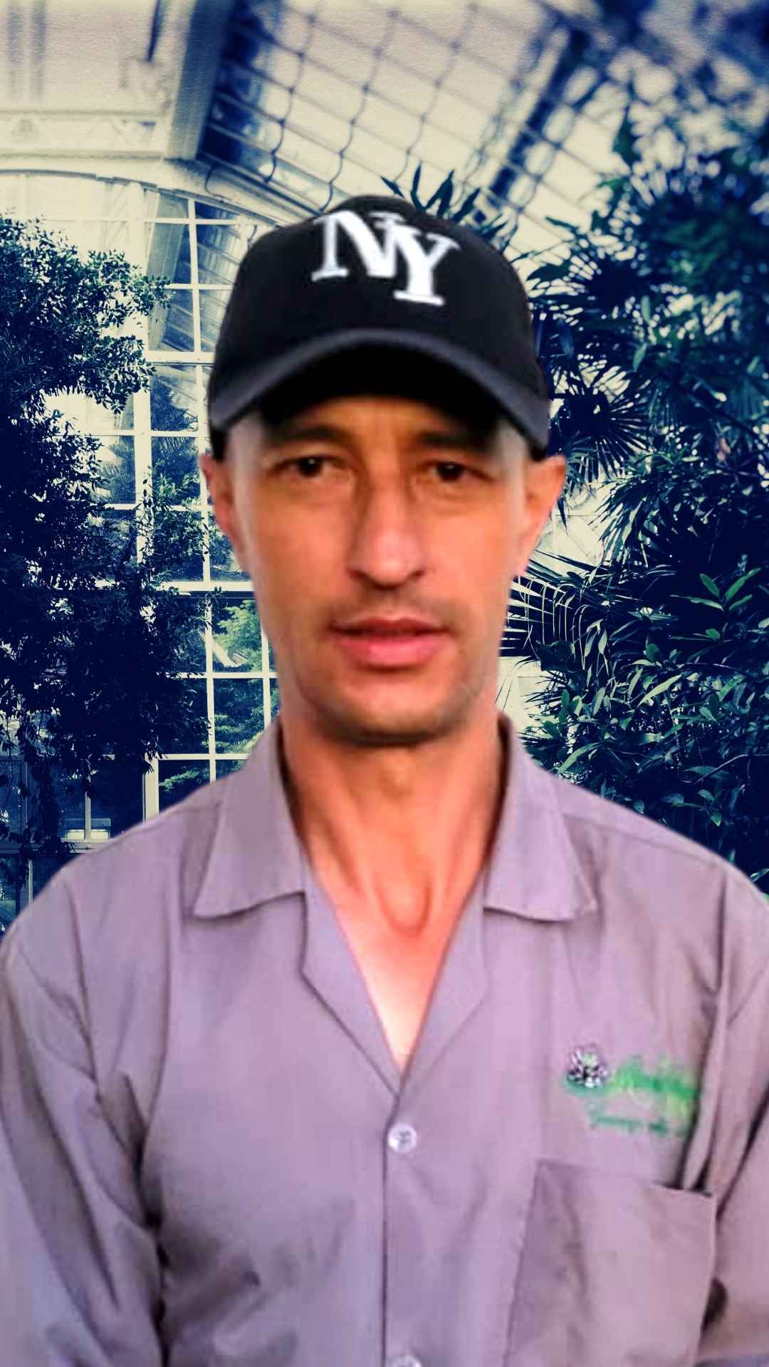 un hombre que llevaba un sombrero ny y una camisa morada