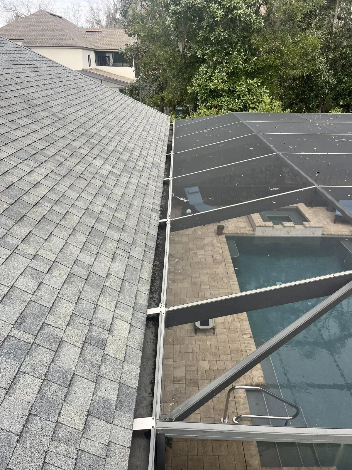A gutter on the roof of a house next to a pool.