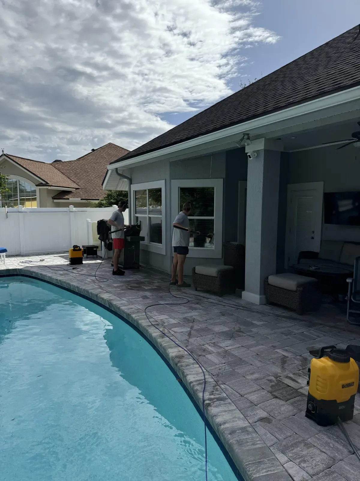 A man is cleaning a window next to a pool.
