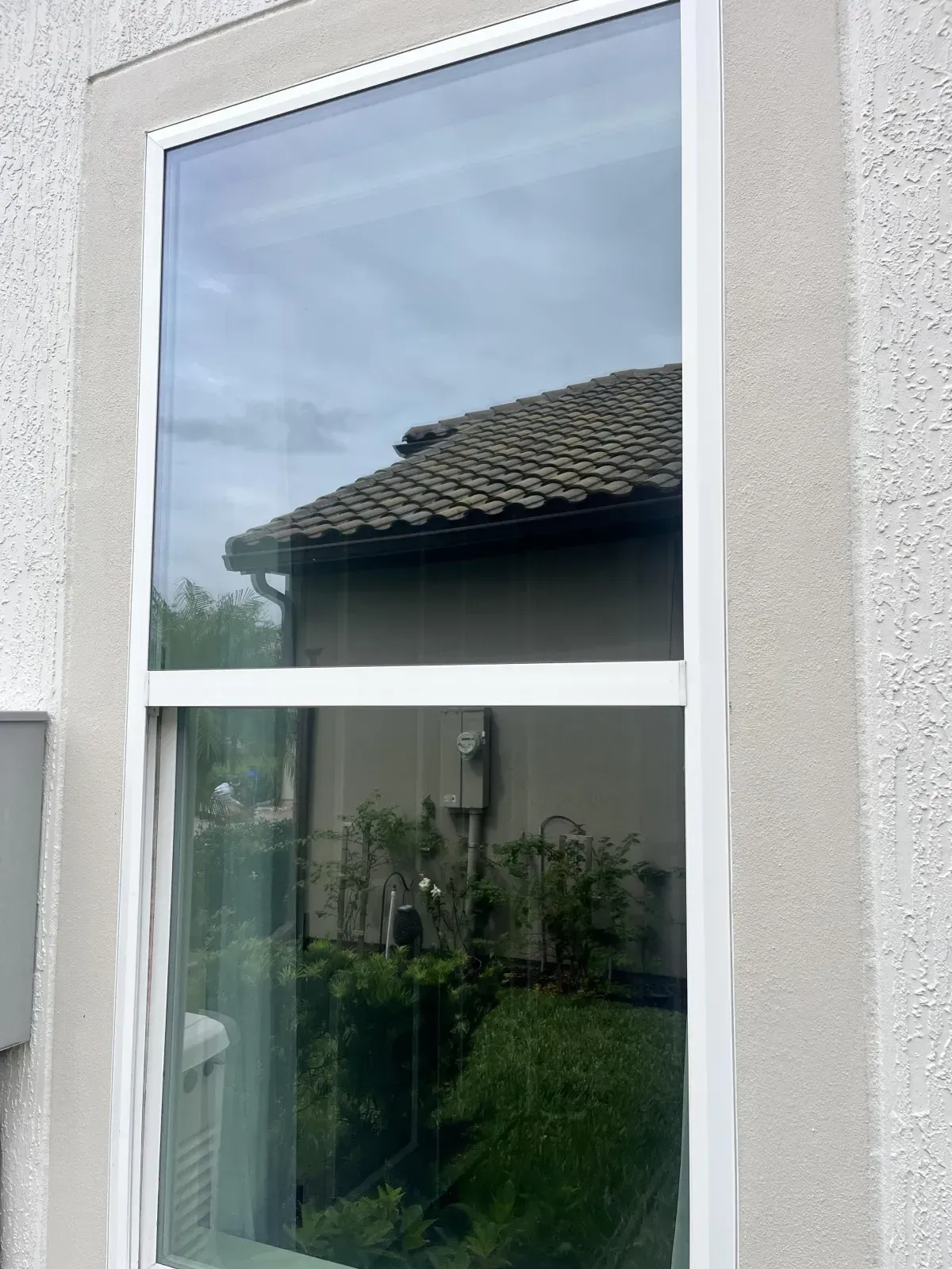 A large window on the side of a house with a reflection of a house in the window.