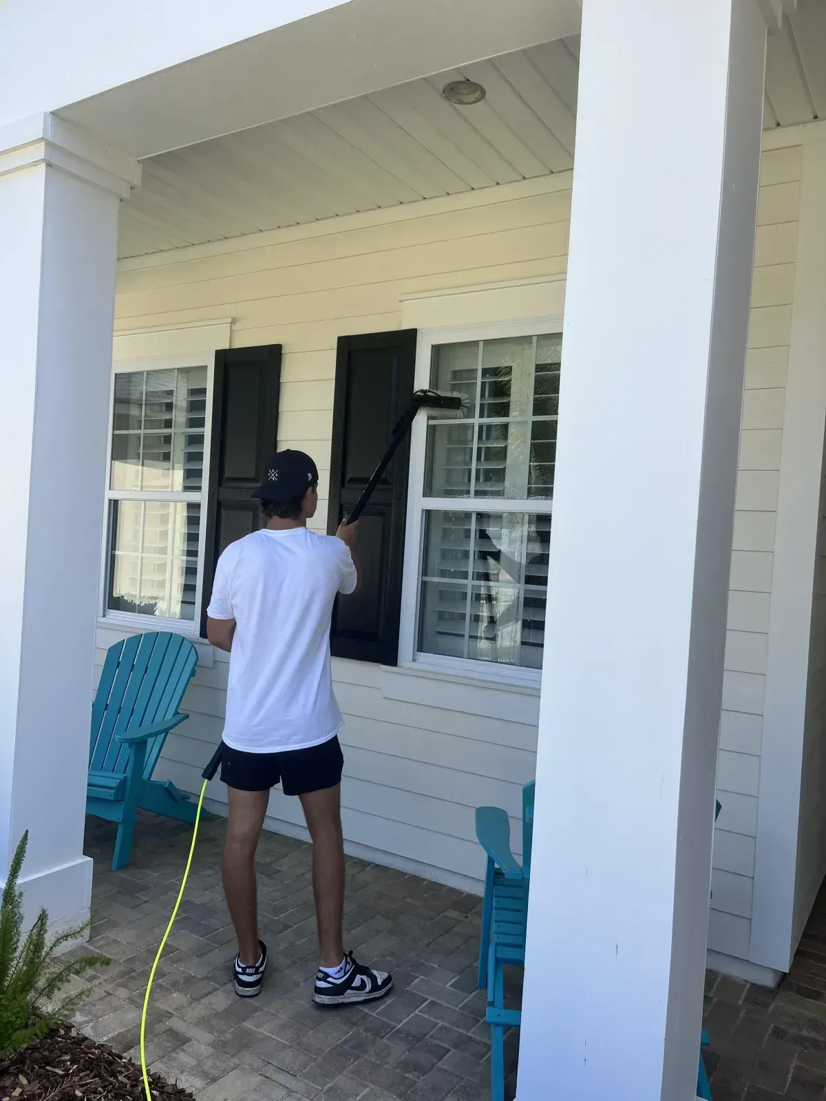 A man is cleaning a window with a vacuum cleaner.