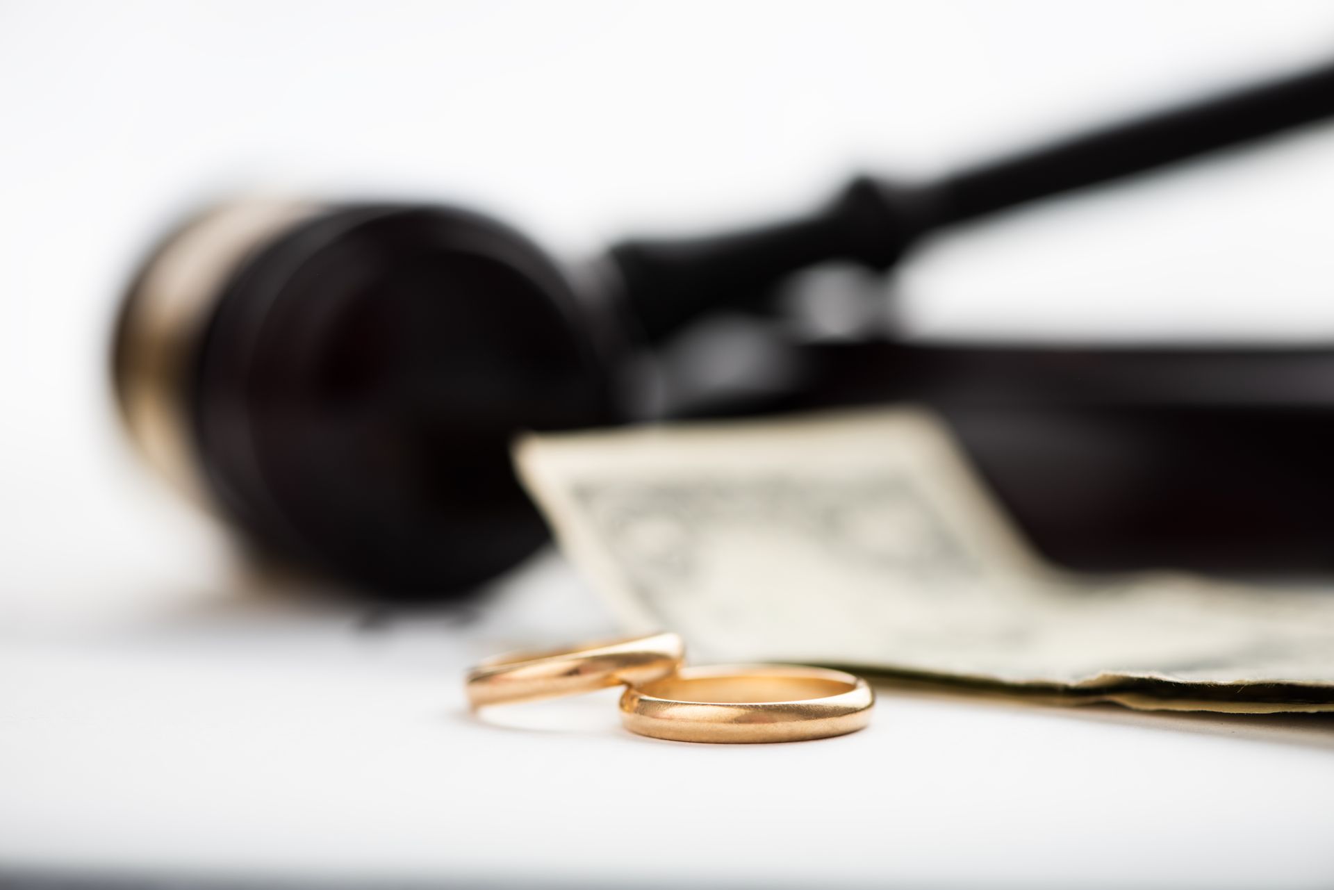A pair of wedding rings sitting on top of a piece of paper next to a gavel.