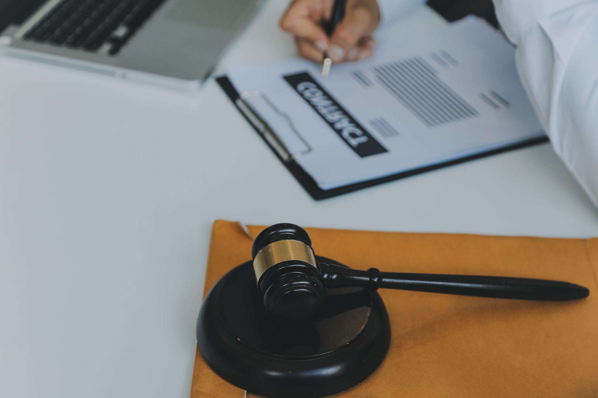 A person is writing on a clipboard next to a judge 's gavel.