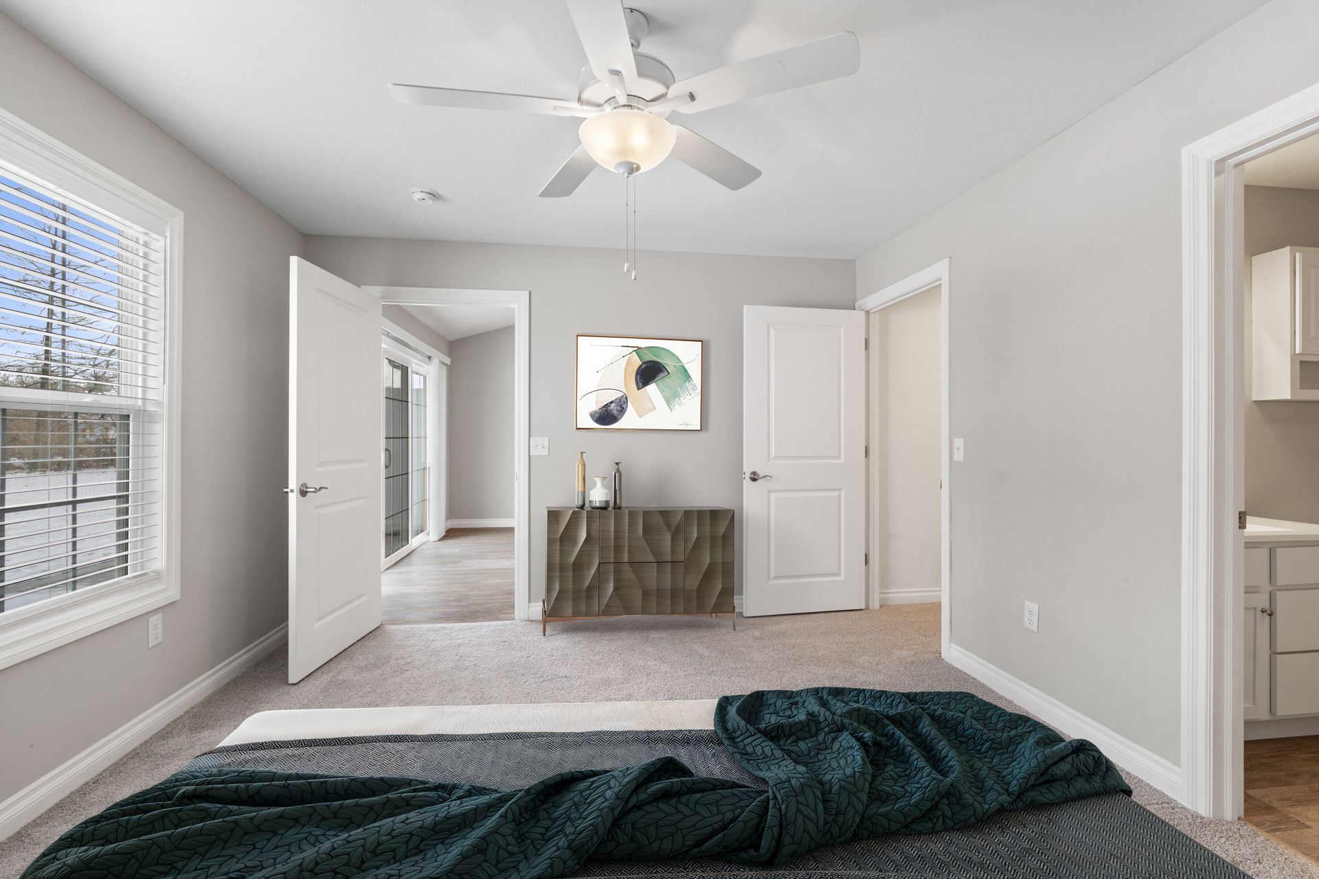 Bedroom with bed, dresser, doors to patio and closet. Gray walls, ceiling fan, and window.
