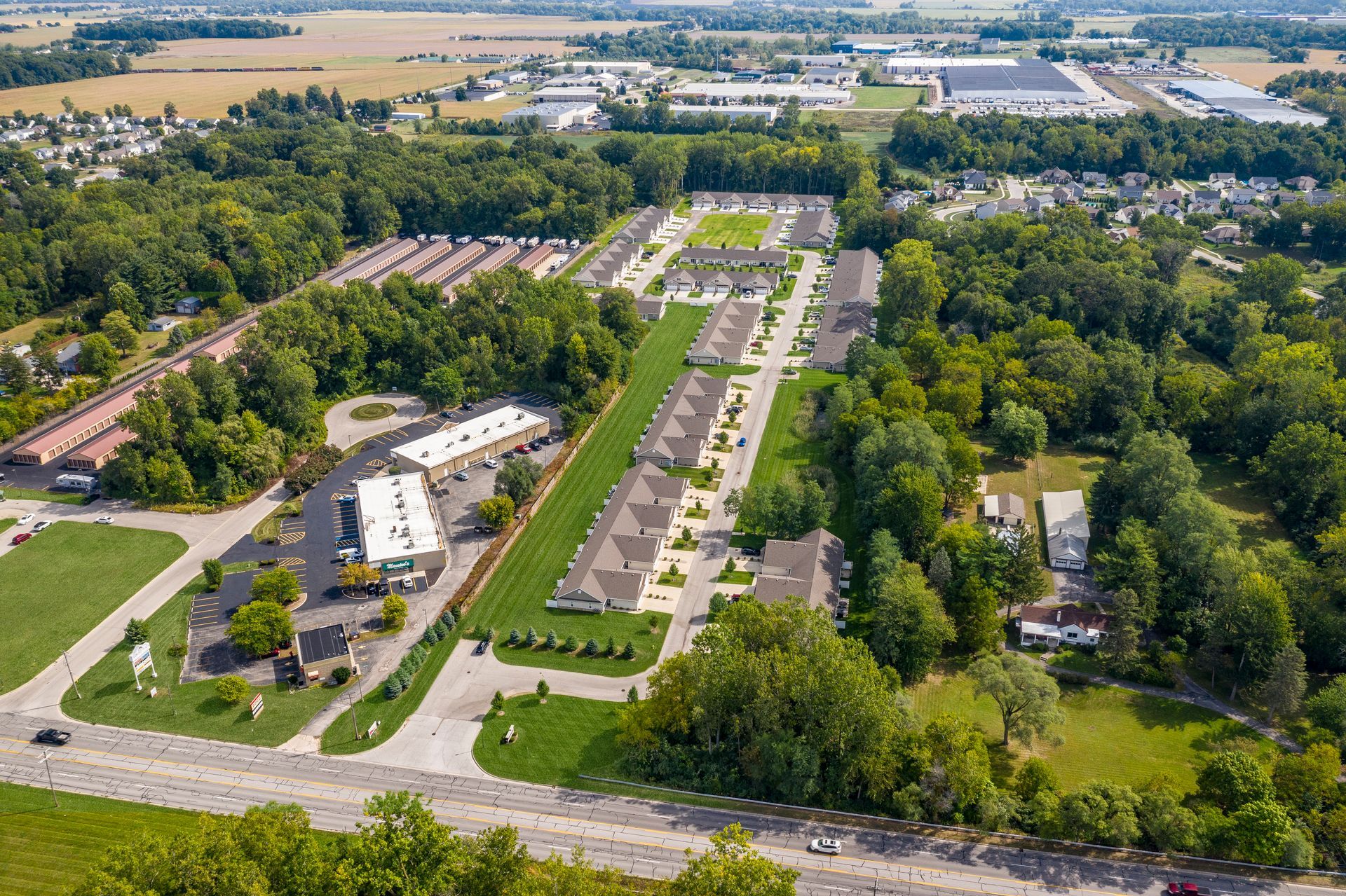 Aerial view of suburban development with townhouses, trees, and commercial buildings.
