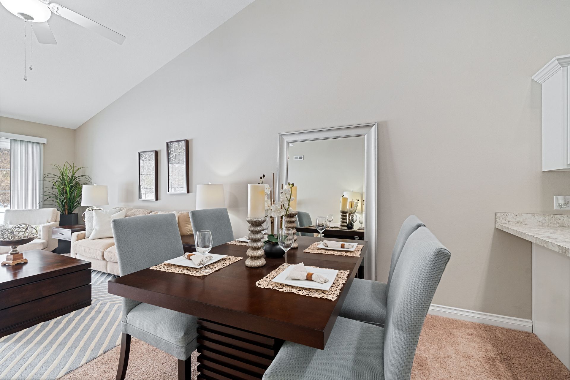 Dining room with dark wood table, blue chairs, large mirror, and open view to living room.