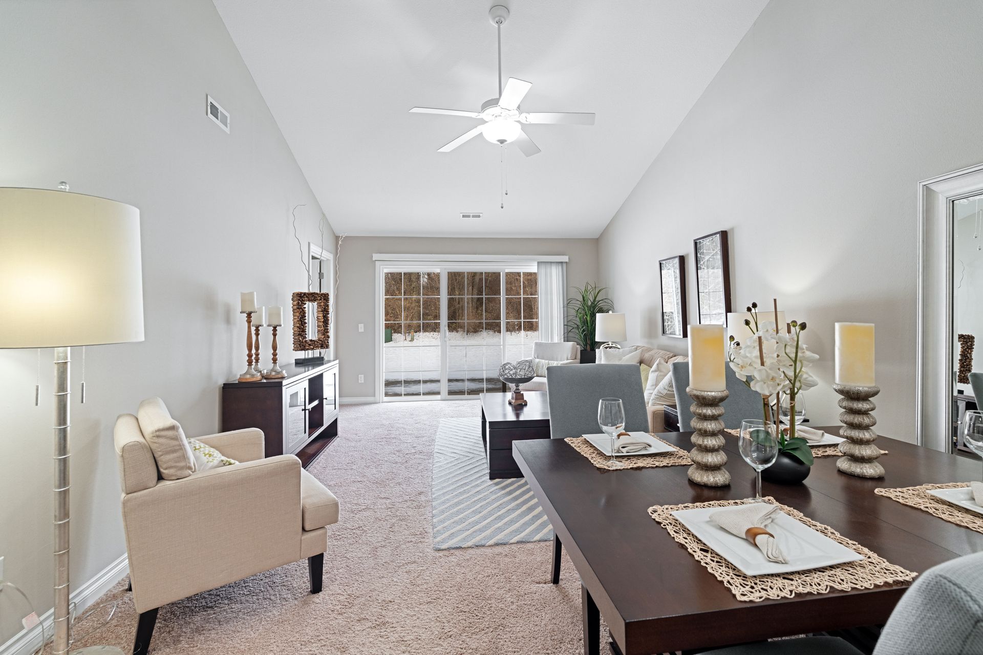 Living room with dining table and seating, neutral tones, and access to a balcony.