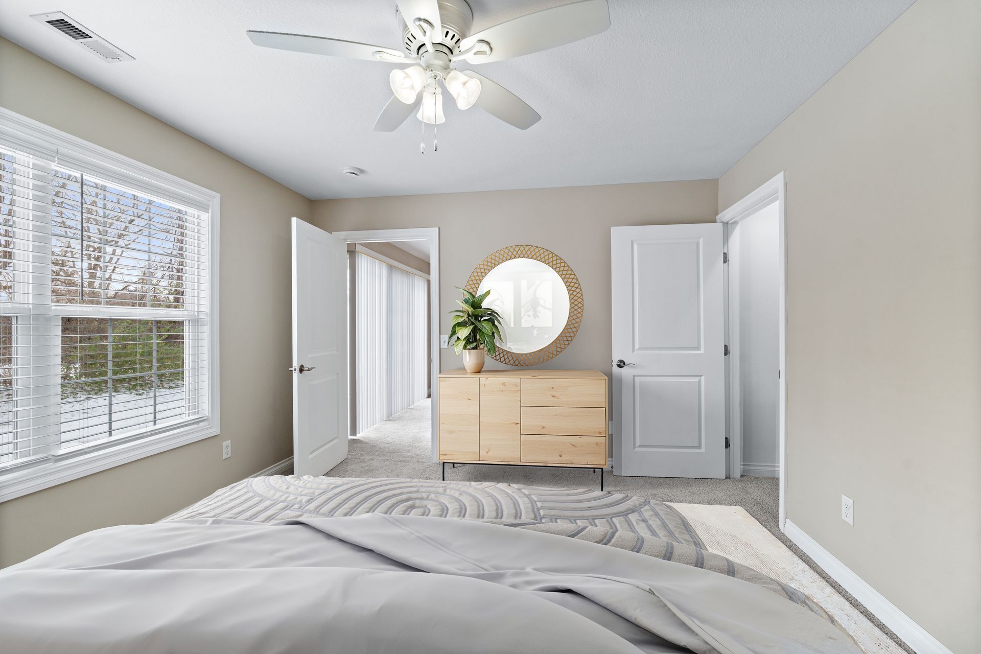 Bedroom with bed, dresser, window, doorway, and ceiling fan. Neutral colors.
