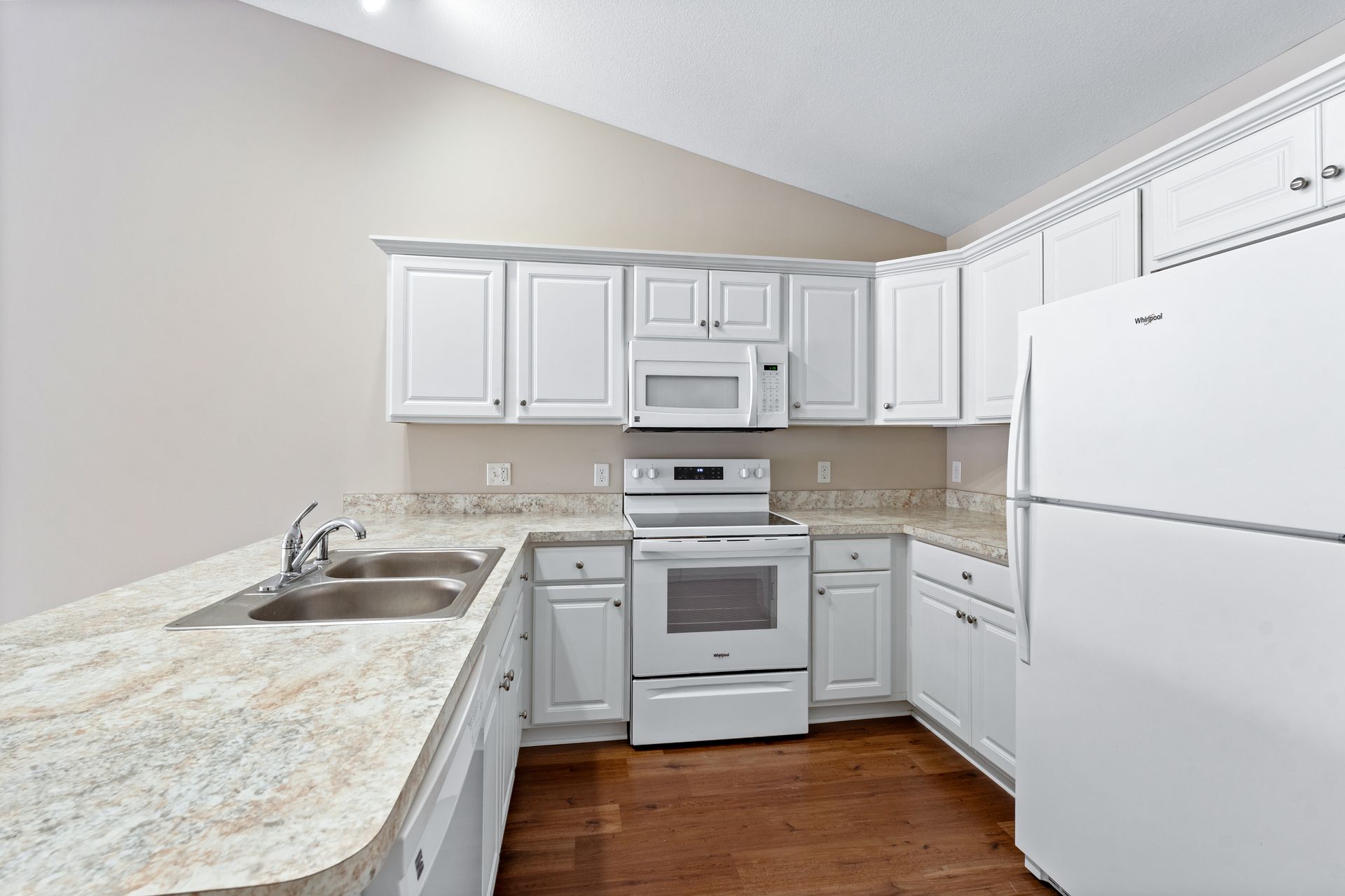 White kitchen with countertops, cabinets, appliances, and a double sink.