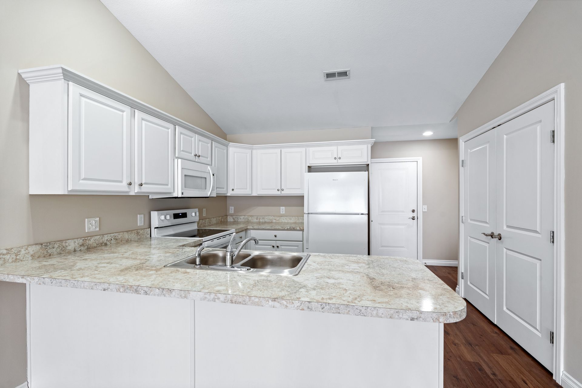 White kitchen with granite countertops, white cabinets, and stainless steel appliances.