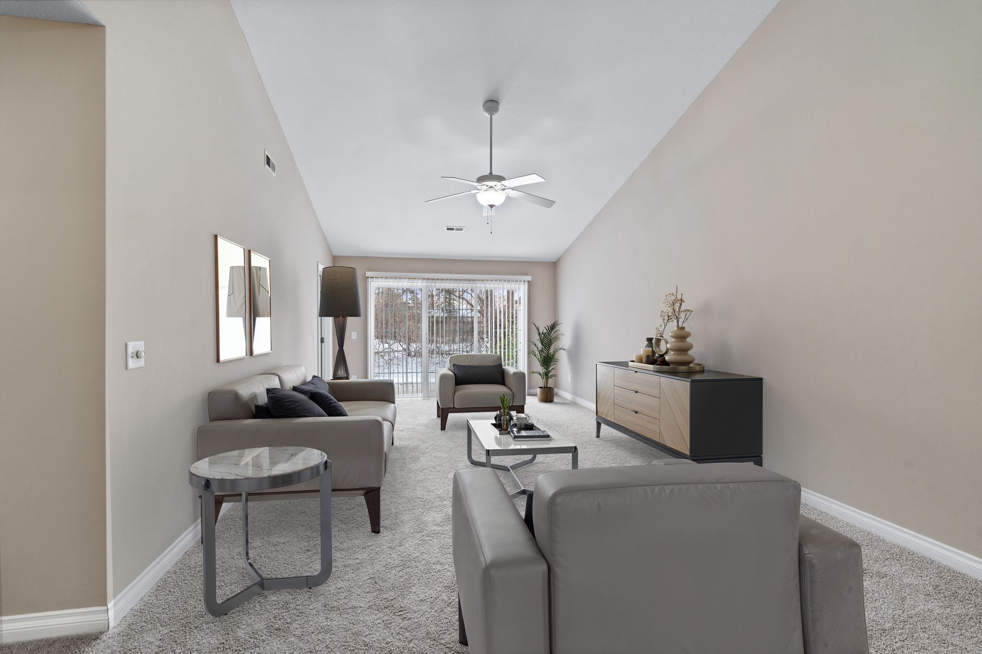 Living room with sofa, chairs, coffee table, and sliding glass door.
