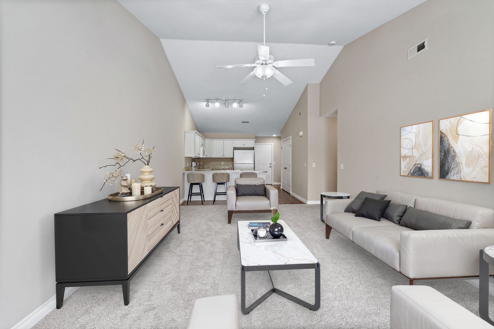Living room with light gray walls, white ceiling fan, sofa, and a coffee table.