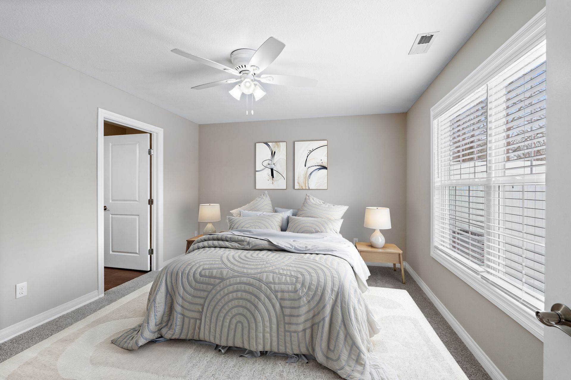 Bedroom with bed, nightstands, window, artwork, and ceiling fan.