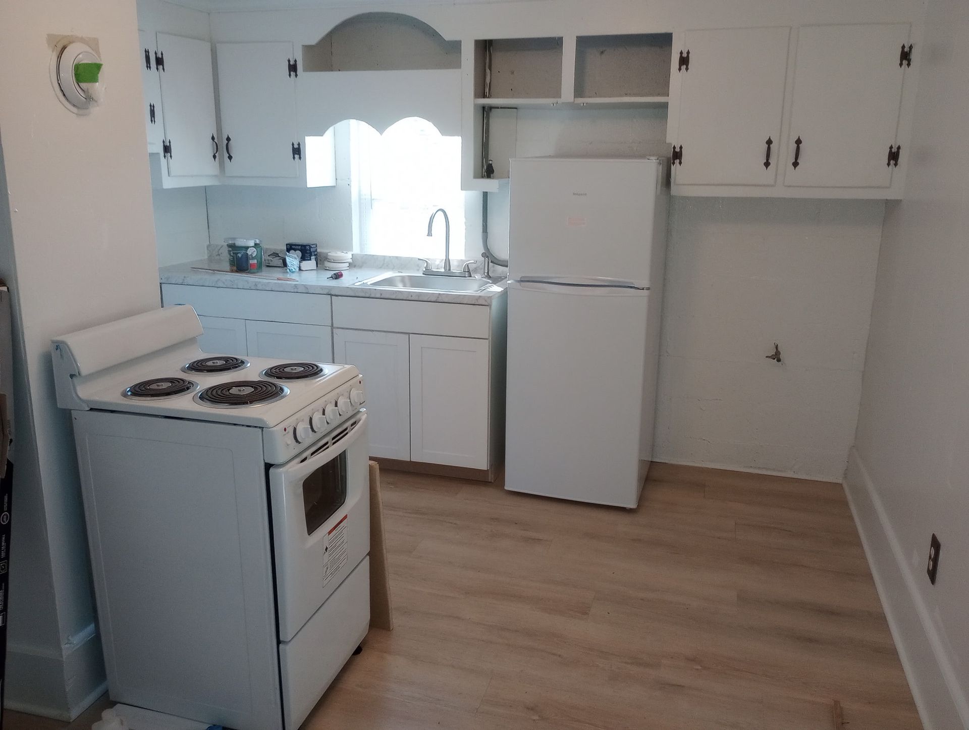 A kitchen with a stove , refrigerator , sink and cabinets