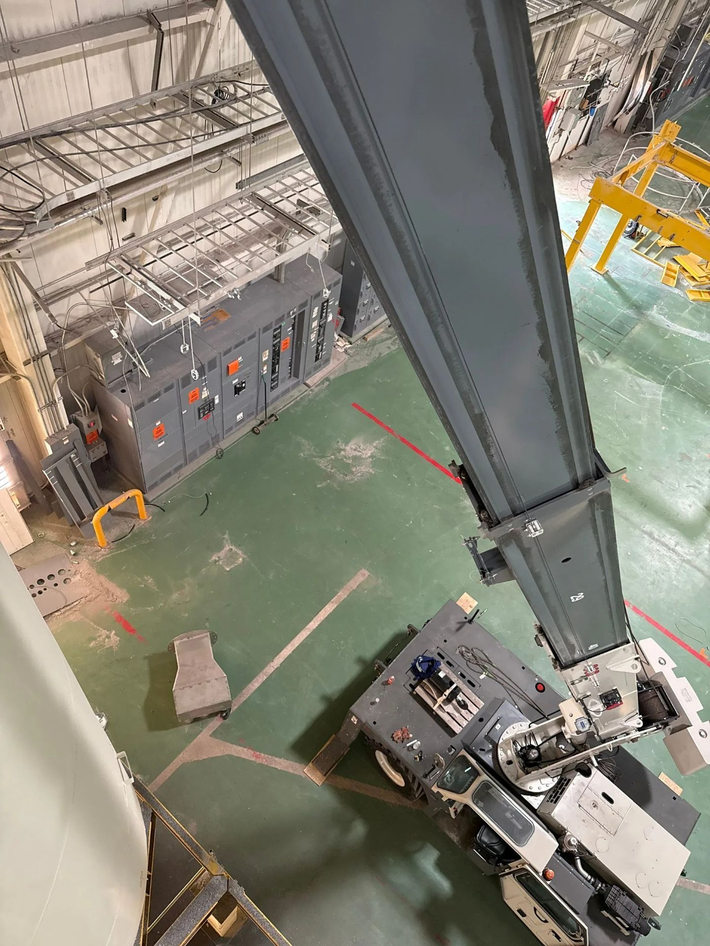 Overhead view of an industrial space with machinery and a large gray crane arm.