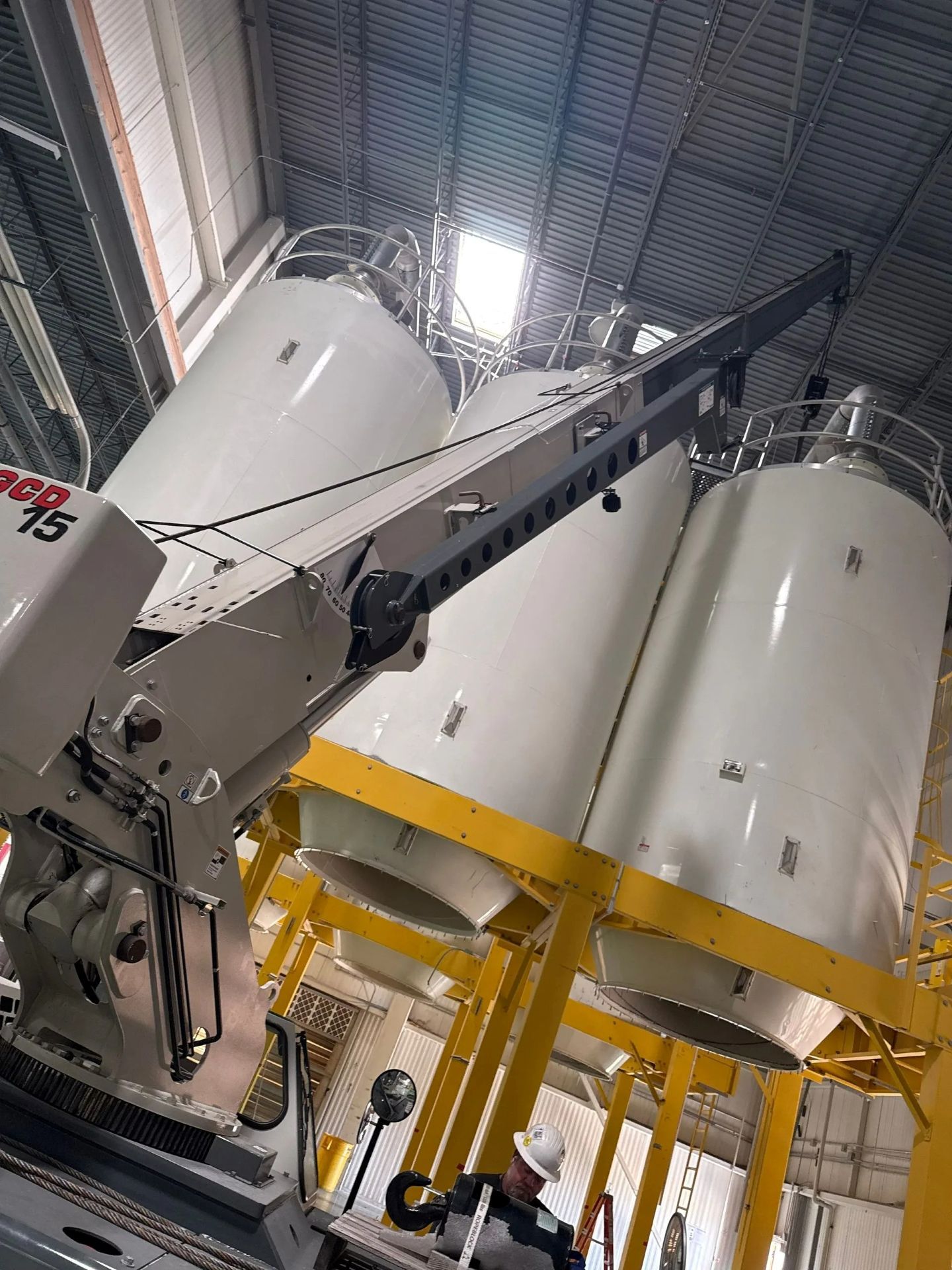 White industrial silos with a crane inside a large warehouse.