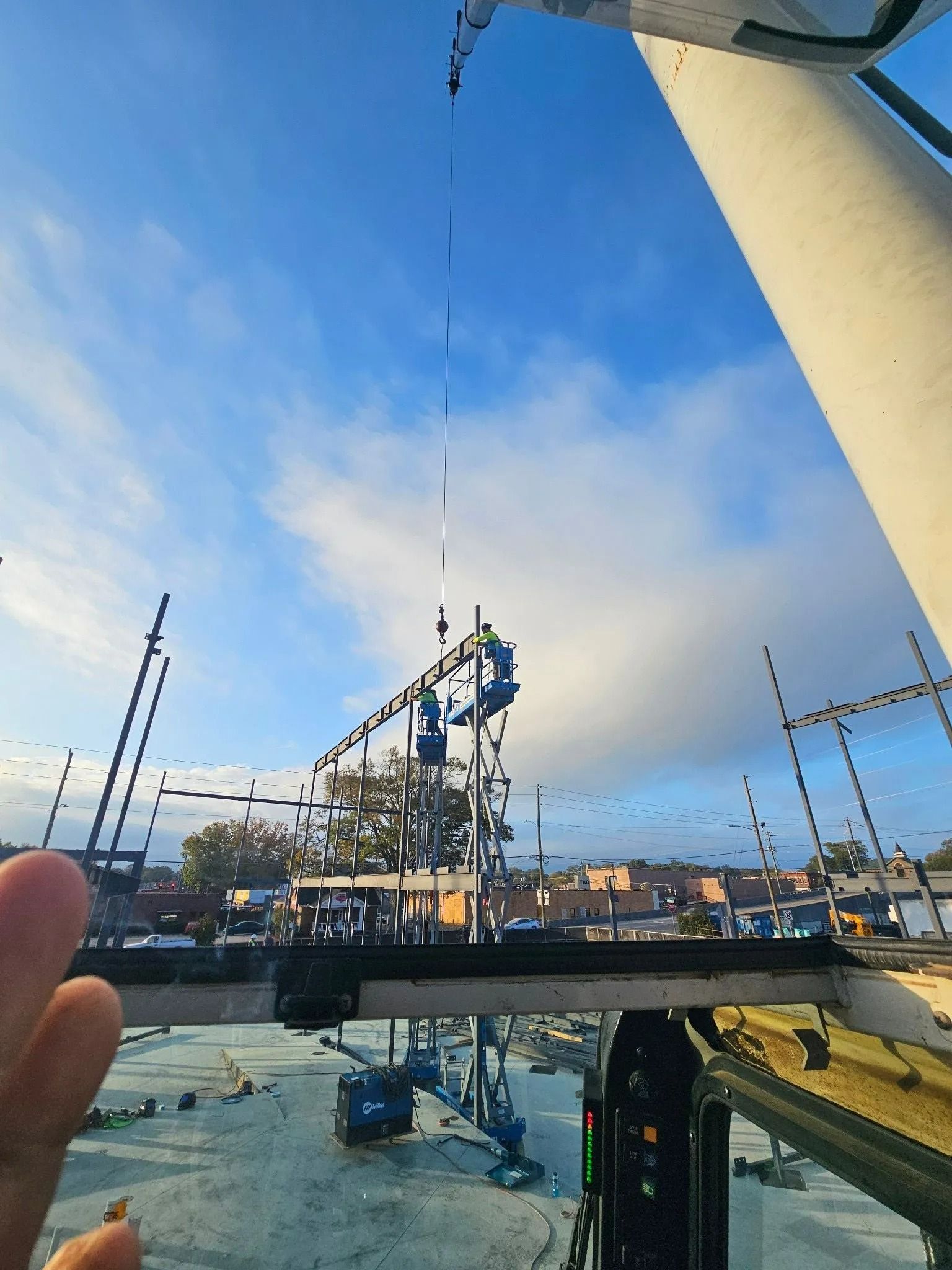 Construction site with crane against a blue sky, buildings in background.