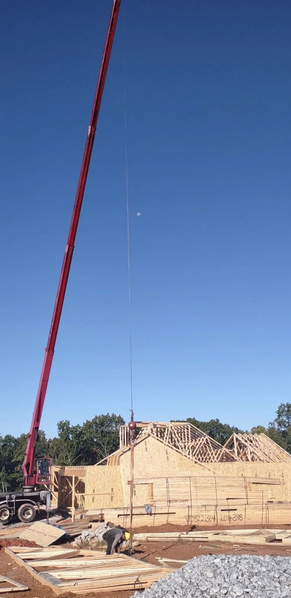 Construction site with a tall red crane against a clear blue sky. A building is being constructed.